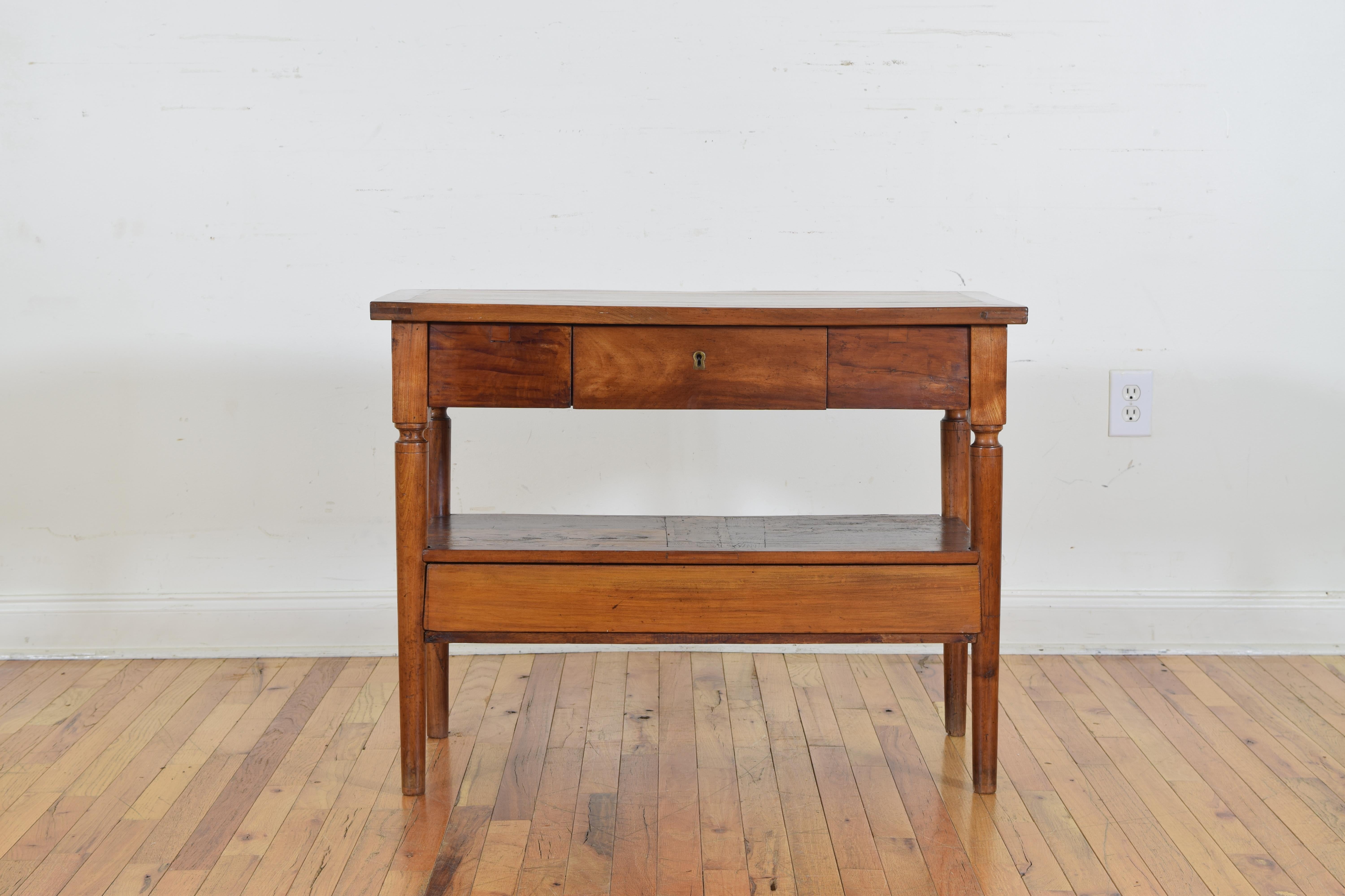 The rectangular top above a conforming case, raised on turned tapering legs, the lower section housing one wide drawer. Second quarter of 19th century.