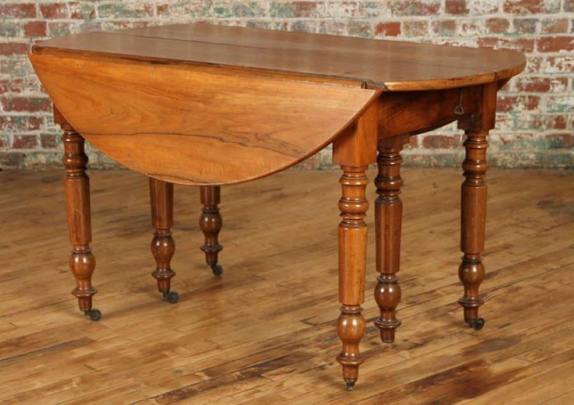 A mid-19th century French Louis Philippe drop-leaf table, in walnut. The almost-round top expands to accept additional leaves (missing) with turned legs on casters and 2 central support legs. Great size for an apartment or small kitchen.