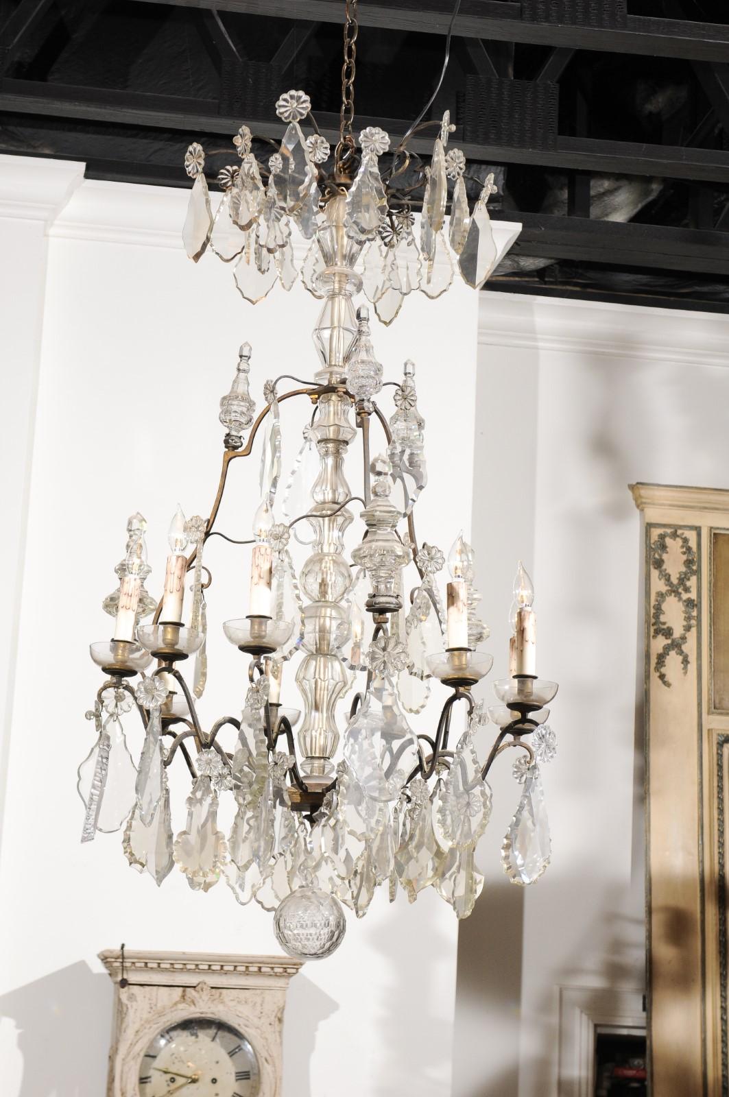 A French nine-light crystal chandelier from the mid-19th century, with iron armature. Born in France during the reign of King Louis-Philippe, this exquisite chandelier features a central crystal column, surrounded by a ring of pendeloques and