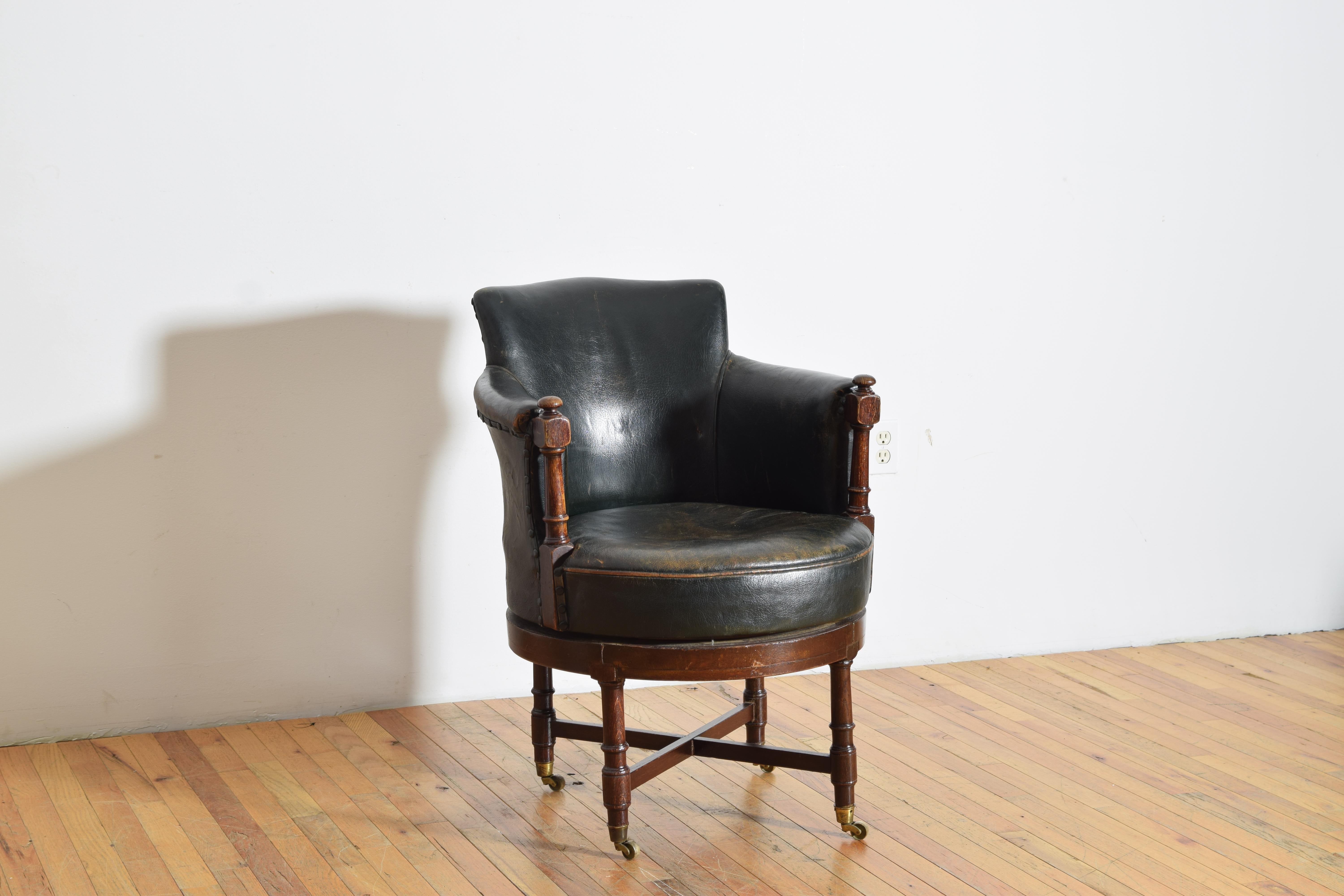 mit abgerundeter Rückenlehne und Seiten mit gedrechselten Armstützen, Sitz und Rückenlehne mit antikem Leder gepolstert, der drehbare Sitz auf einem angepassten Rahmen, der auf gedrechselten Beinen mit Messingrädern steht