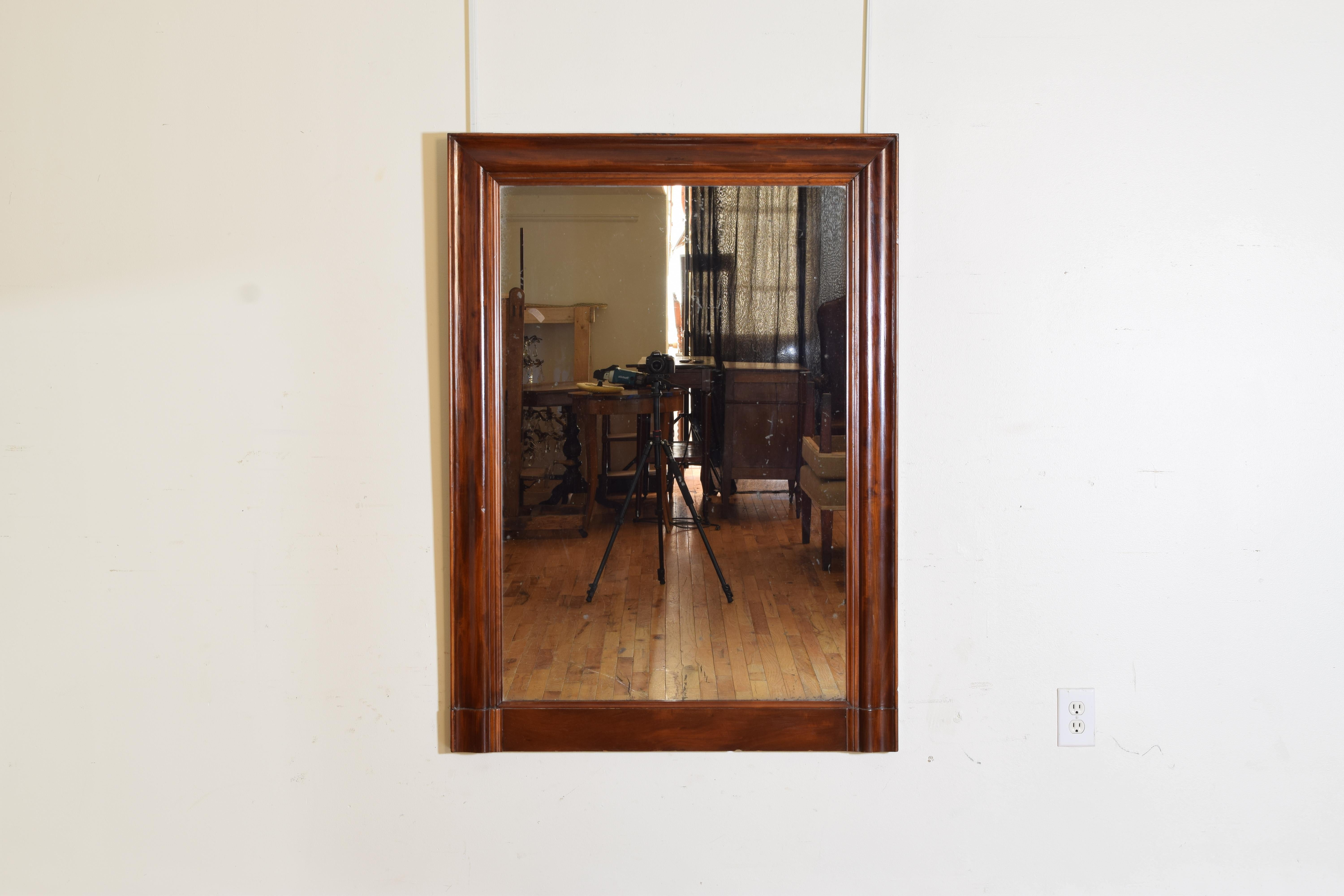Of rectangular form and constructed entirely of cherry wood with shaped wave-form sides and interior and exterior moldings, retaining original heavy mirror plate.