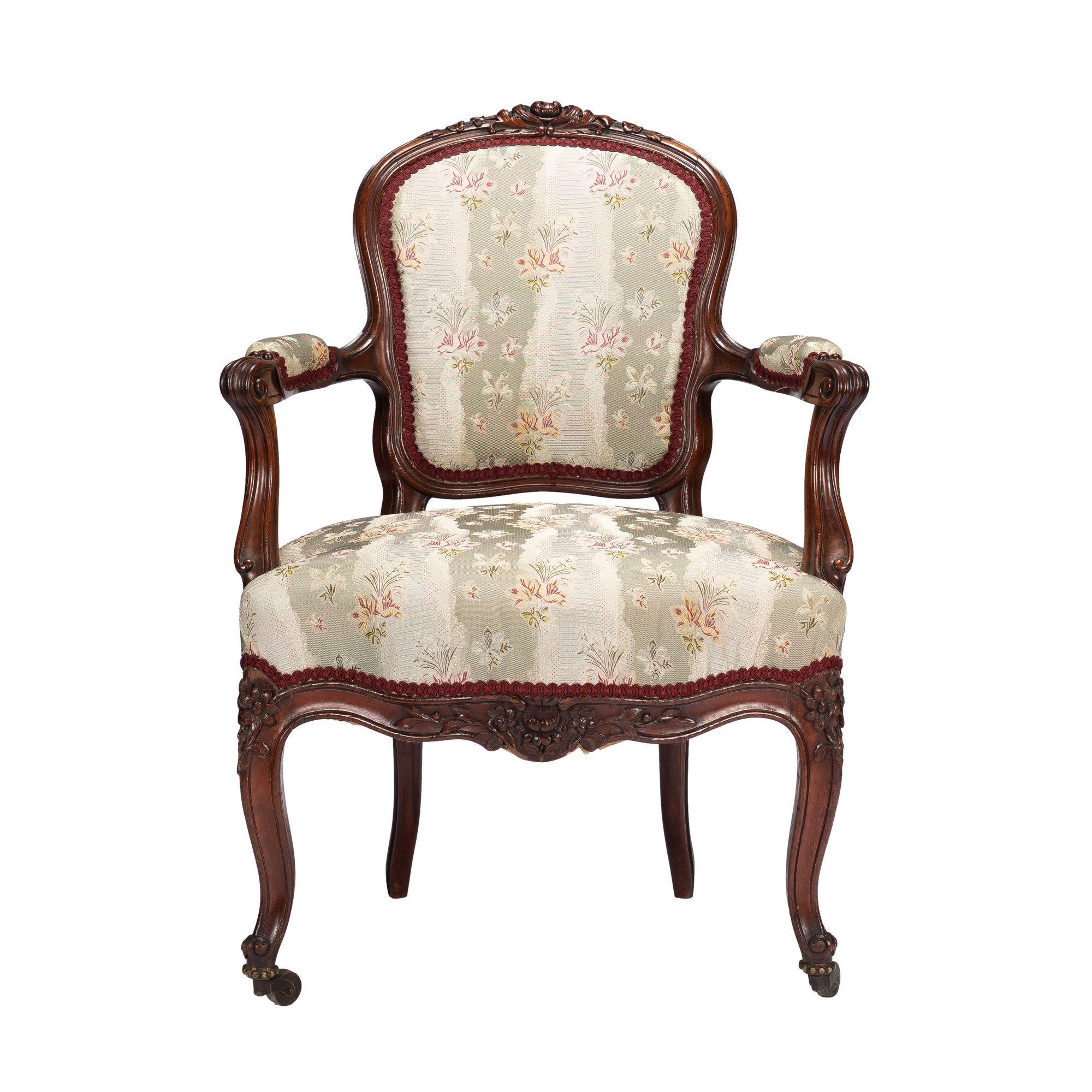 Louis Philippe Period walnut fauteuil, upholstered in silk brocade in the Louis XVl taste. Beautifully proportioned and carved with its cabriole legs terminating in their original castor feet. Accompanied by a paired footstool in matching silk
