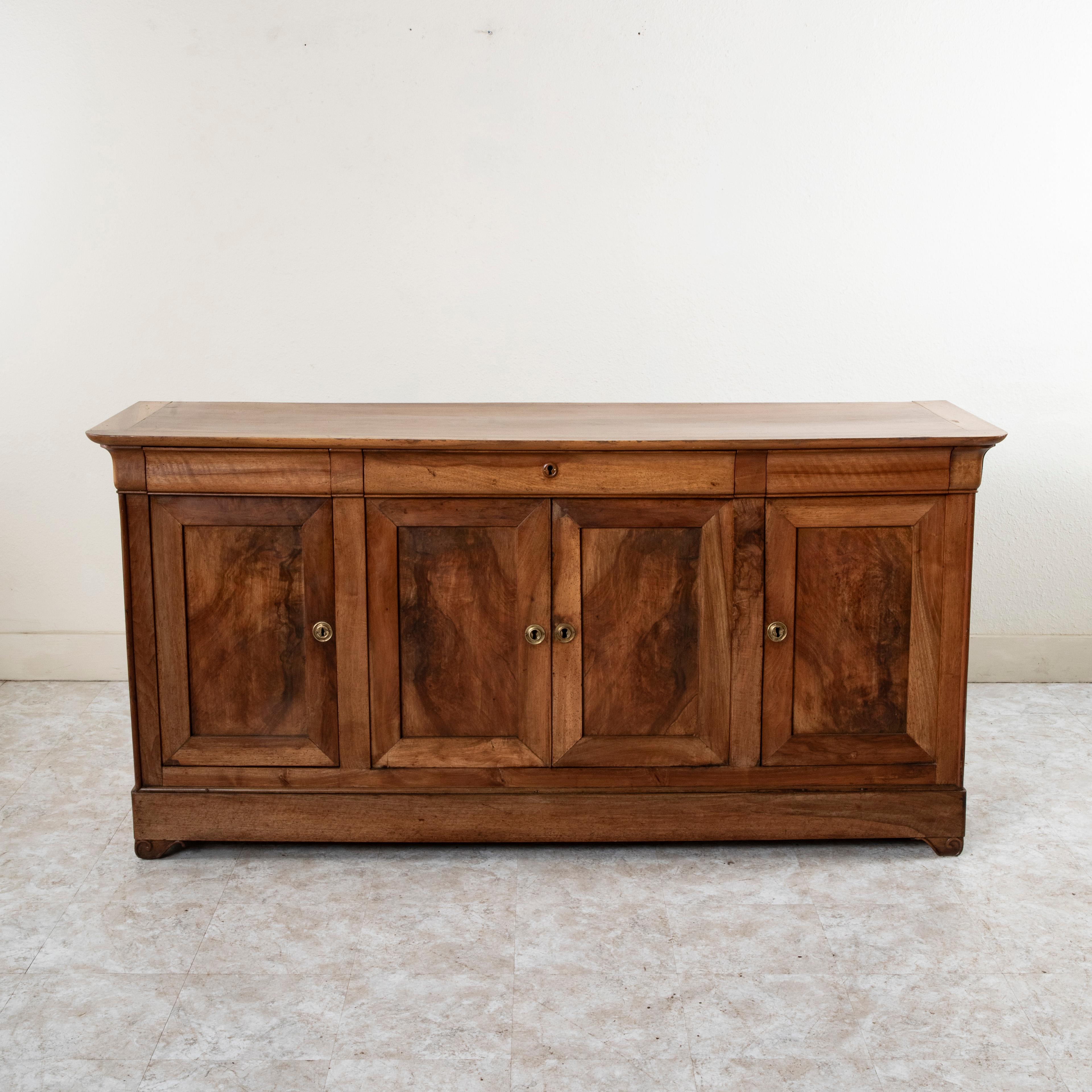 This French Louis Philippe period enfilade or sideboard from the mid-nineteenth century is constructed of solid walnut. This server features three drawers of dovetail construction that fit seamlessly into the apron below the top. Below are four