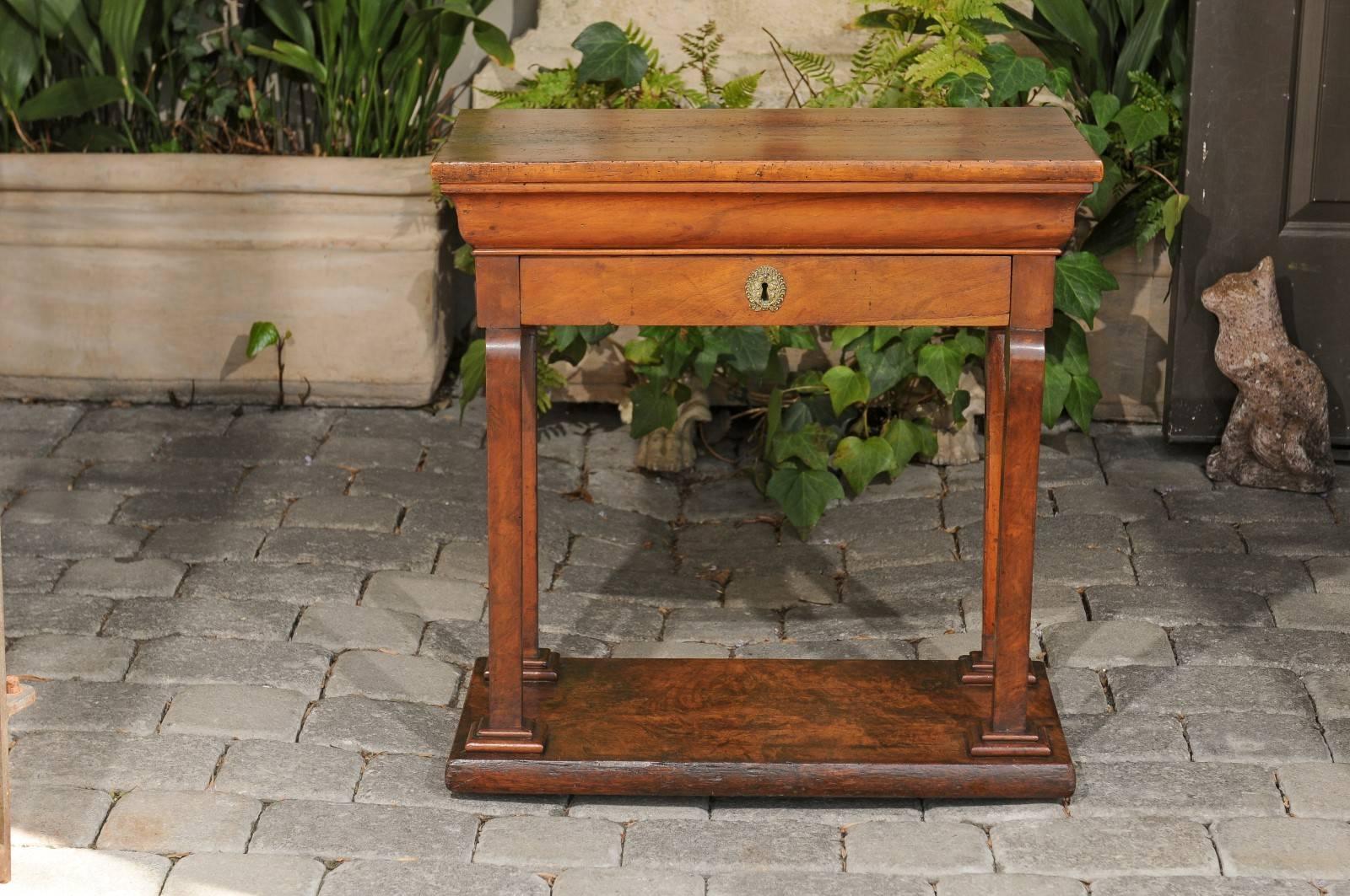 A French period Louis-Philippe walnut side table from the mid-19th century with single drawer, scrolled legs and lower shelf. This French side table features a nicely weathered rectangular top sitting above a delicately curved apron, surmounting a