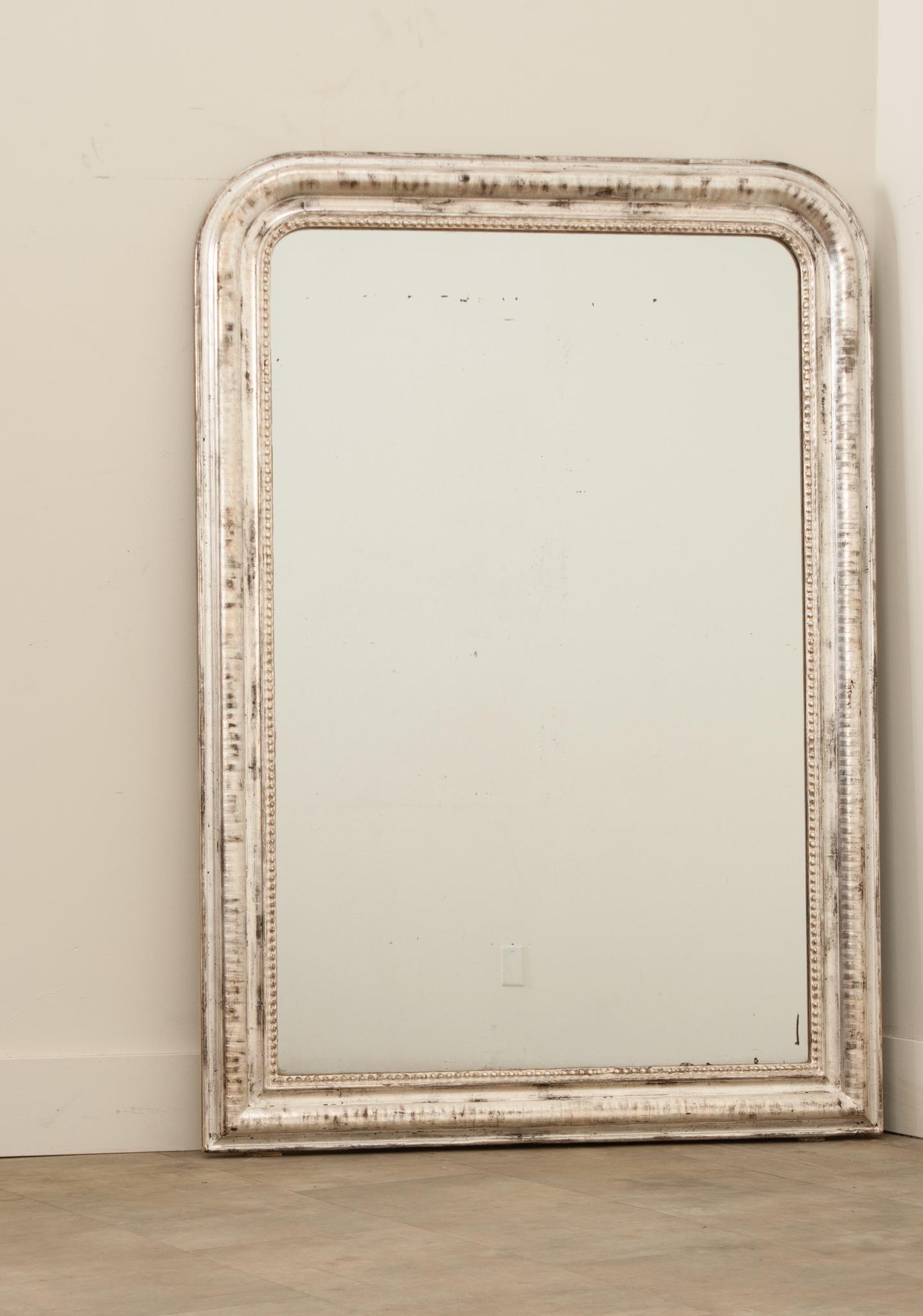 A silver gilt Louis Philippe style mirror hand-crafted in France in the 19th century. Rectangular in shape with rounded corners that create an elegant and timeless shape, the molded frame is decorated with luxurious silver leaf finish over etched