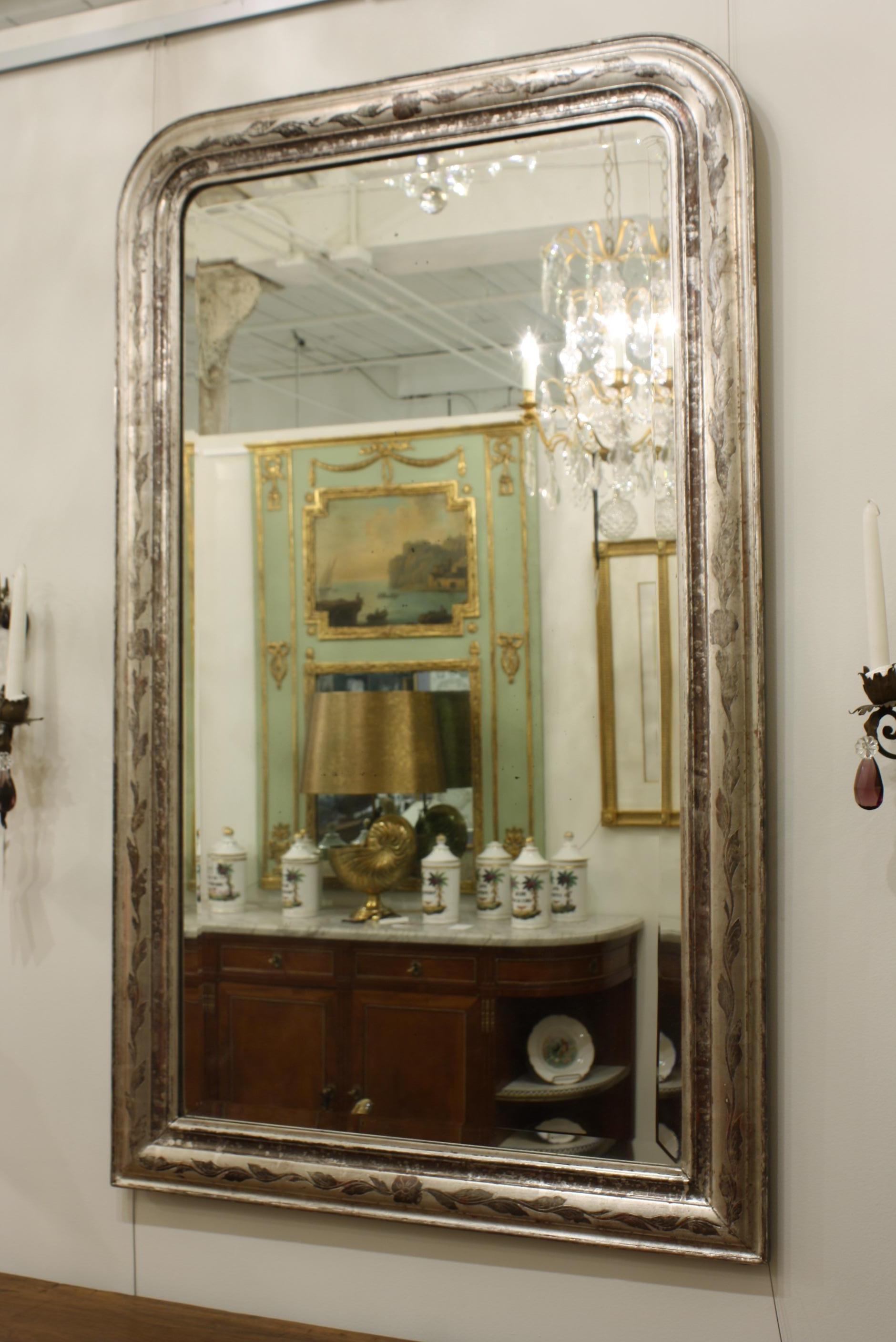 French antique Louis-Philippe mirror with silver leaf gilt frame decorated with vine and leaf design. Includes the original bevelled mirror glass, which shows some age. The silver gilt also show some spotting.