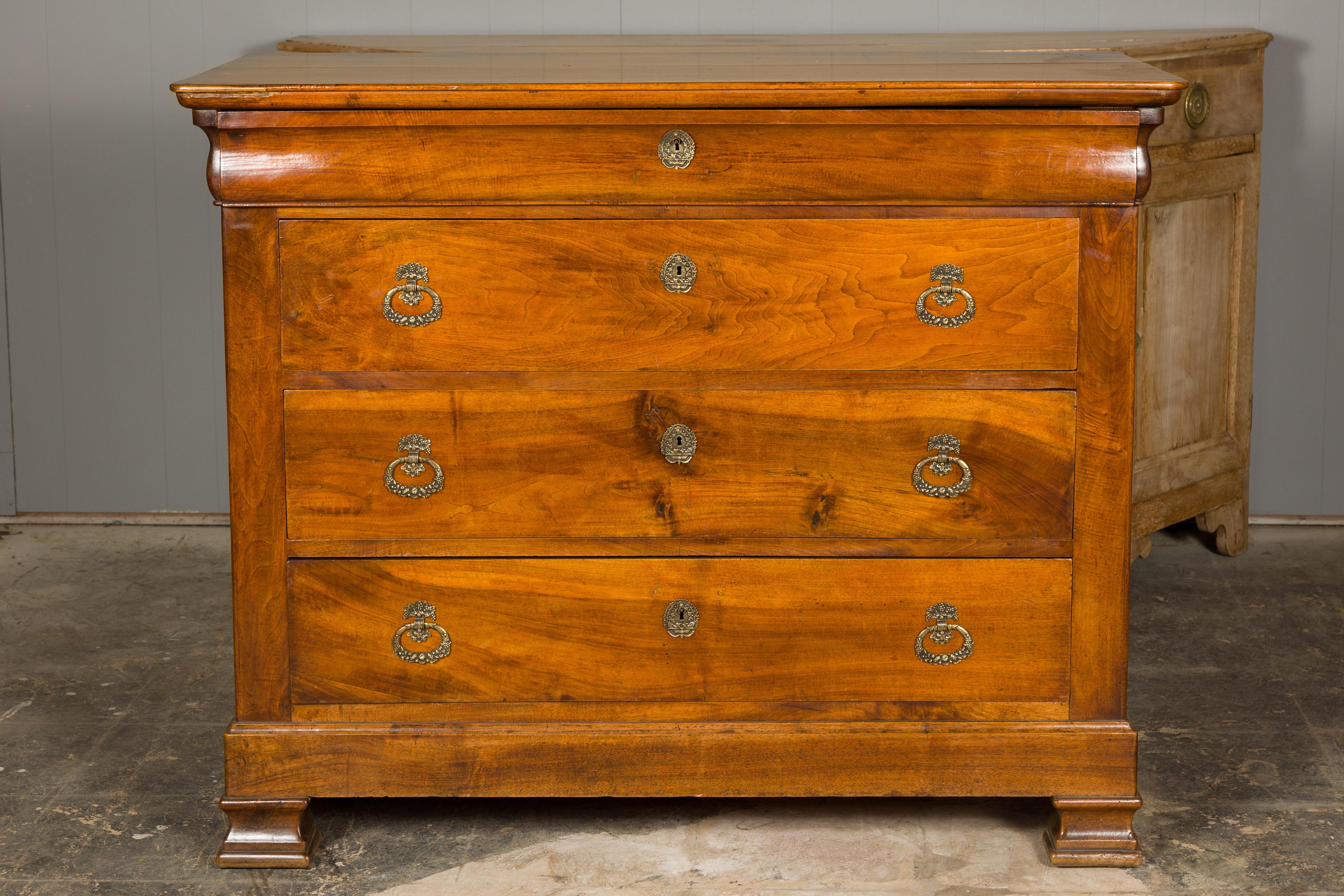 A French Louis Philippe style wooden commode from the 19th century with four drawers, ornate brass hardware and carved feet. Elevate your living space with this exquisite French Louis Philippe style wooden commode from the 19th century. Crafted with