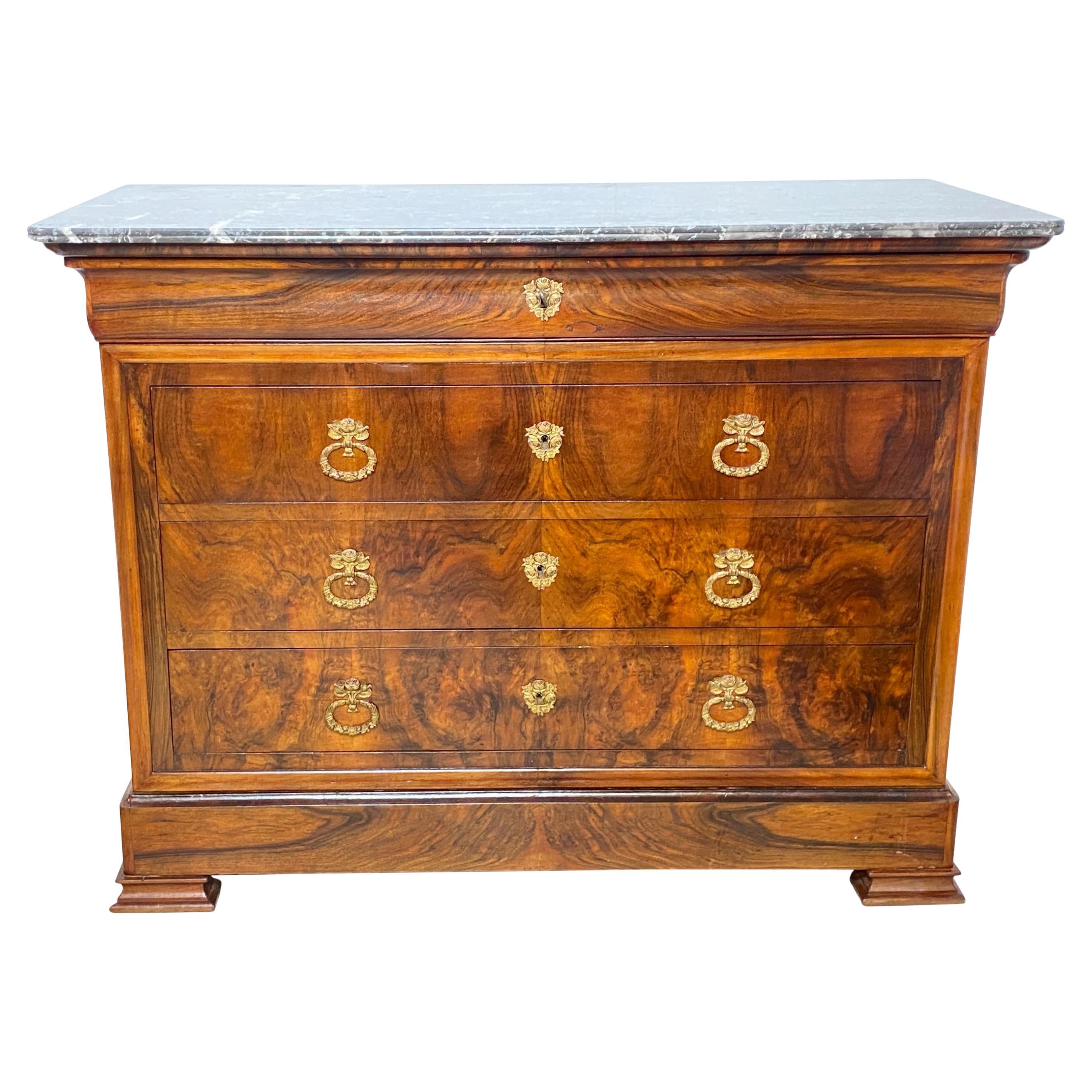 This Louis Philippe period commode or chest of drawers displays the exemplary craftsmanship of the early nineteenth century with figural burl walnut and solid walnut panel sides, and capped with a marble top. Having four drawers with bronze original