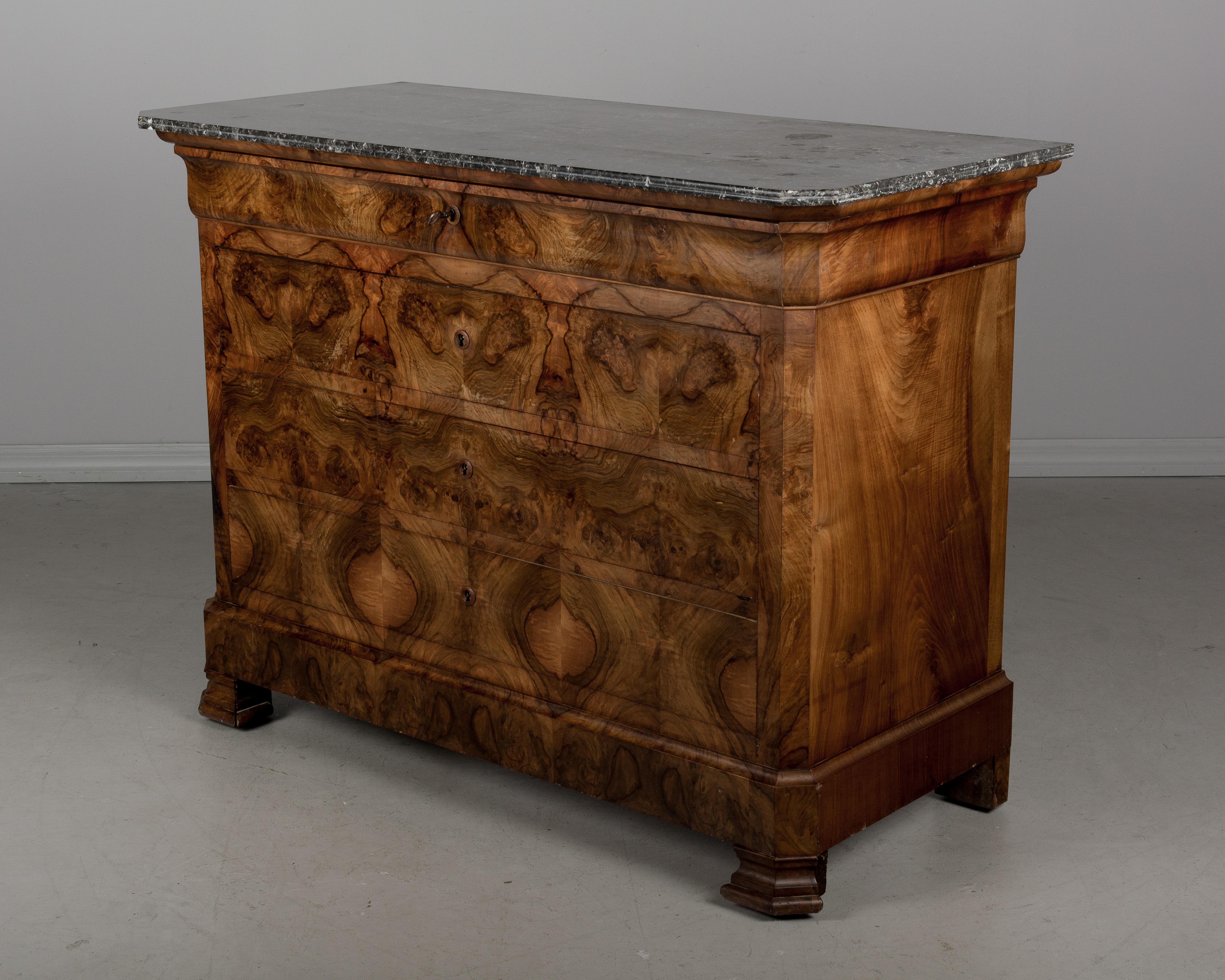 A French Louis Philippe style commode with five dovetailed drawers and original St. Anne grey marble top. Front has beautifully patterned book-matched veneer of walnut. Four locks are in working order, with one key. Note: two pieces of trim are