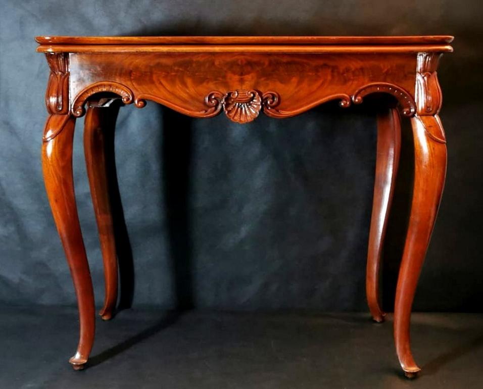 Elegant game table made of polished light sapele wood. The edge is decorated with delicate and harmonious motifs, and the legs have a soft saber shape. The top is hinged so that it can be opened, expanding the table's dimensions to 89 x 88 cm. Under