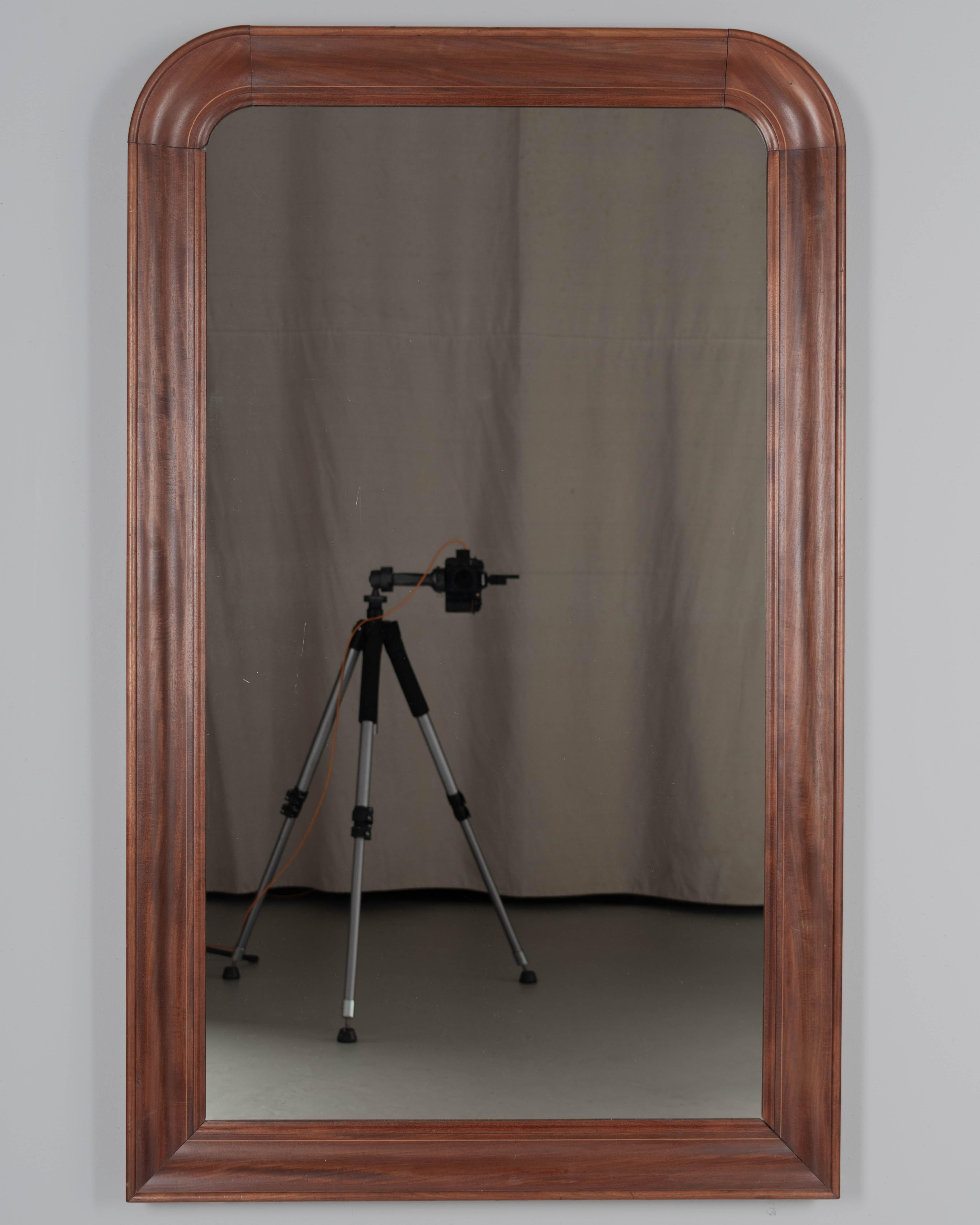 A French Louis Philippe style mirror with solid mahogany frame, curved top corners and fine inlaid detail. in good condition with very slight corner separation. Original mirror. Circa 1950s. 
Dimensions: 33