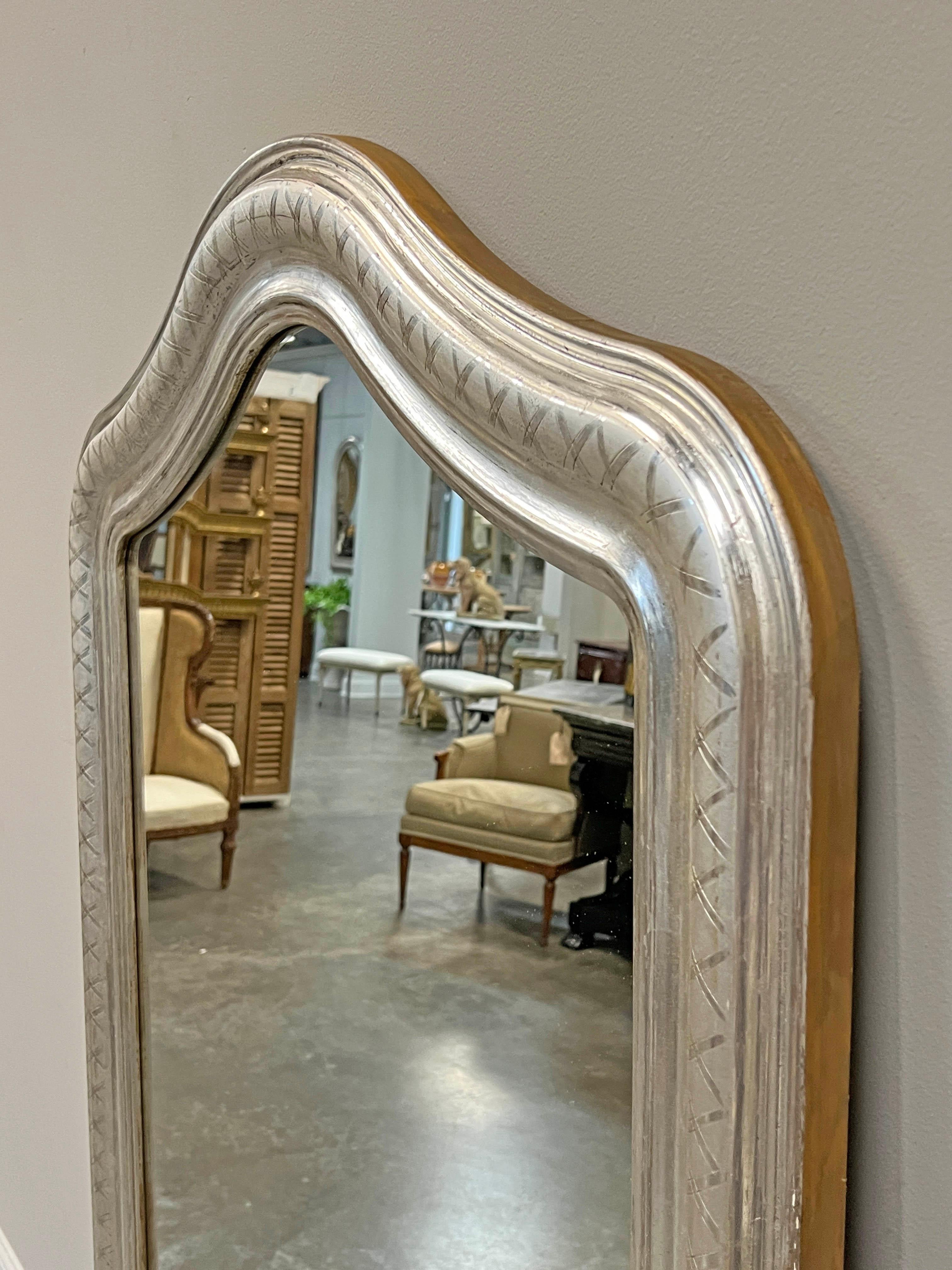 Miroir de style Louis Philippe en argent doré, avec un motif de treillis sur le cadre et un chapeau de gendarme sur le dessus.