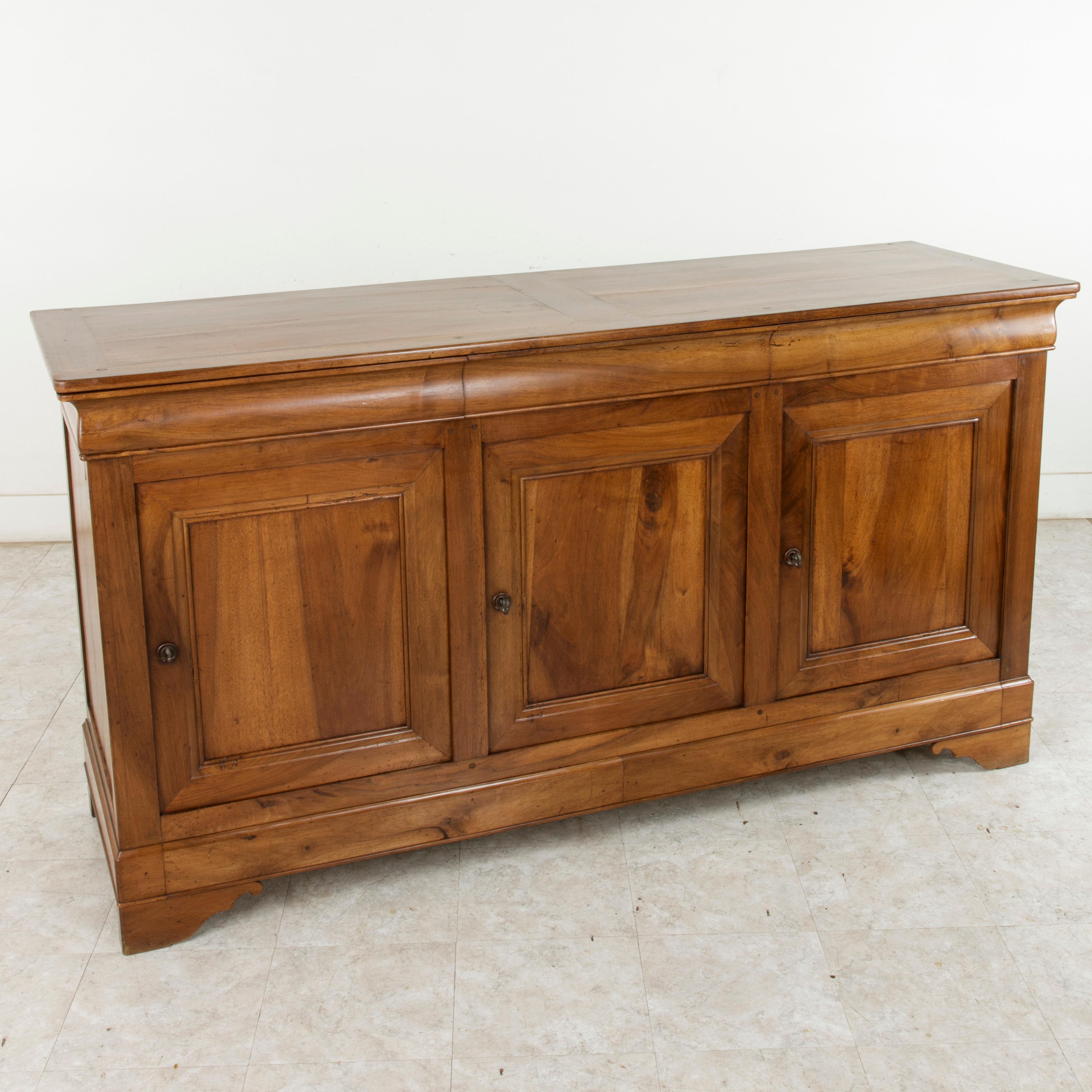 This French Louis Philippe style enfilade or sideboard from the turn of the twentieth century is constructed of solid hand walnut with hand pegged joinery. This server features three drawers that fit seamlessly into the apron below the top. Below