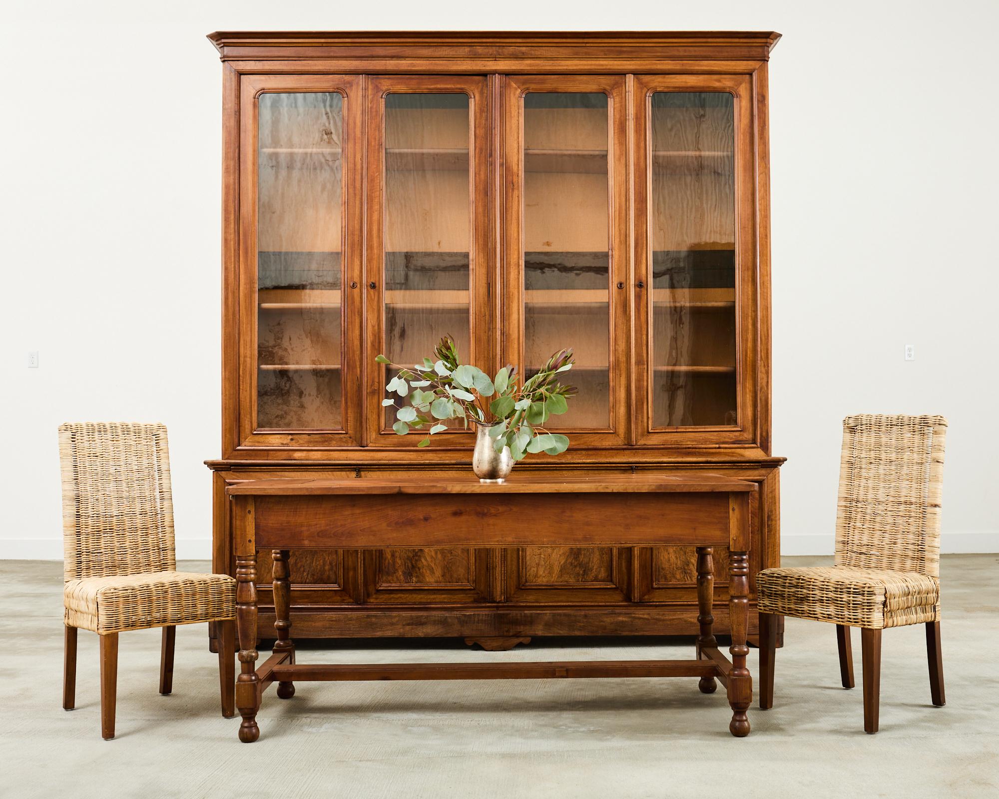 Magnificent early 20th century French library bookcase or bibliotheque cabinet crafted from walnut. The top case features four large doors with period correct wavy glass fronts. The doors open to a shelved interior. The bottom cabinet measures 32