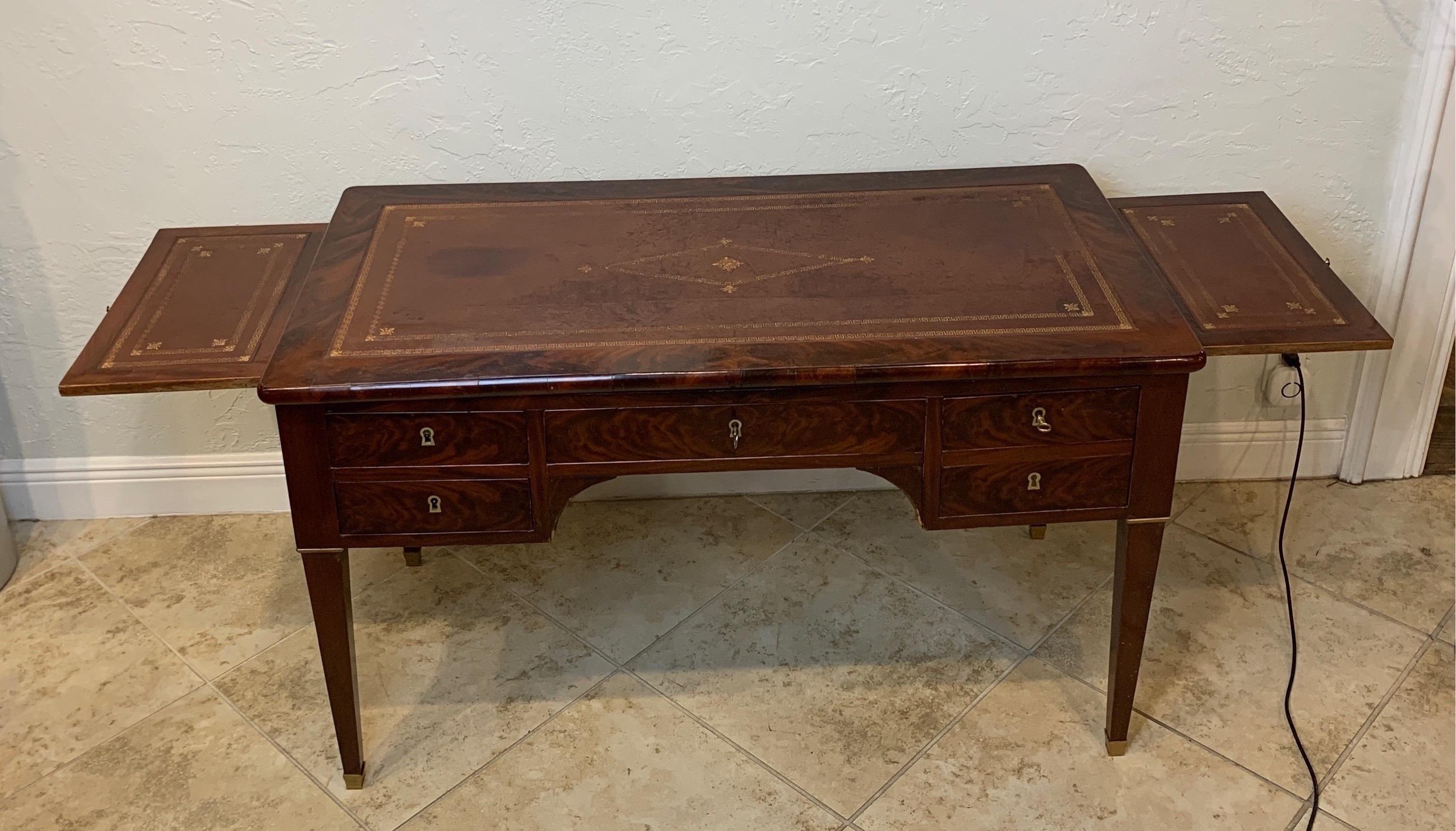 Wonderful 19th century French Louis Philippe writing desk with a tooled leather top. Well figure crotched mahogany. Comes with four drawers and leather writing surfaces pull out on each side. Leather is in good used condition. One drawer reveals a