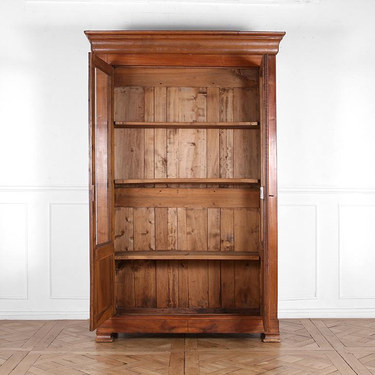 This late 19th century French cabinet features a well made walnut frame with two glass-paneled doors that open to original, solid wood shelving, perfect for books or displaying treasures. Having a simple yet elegant design, it includes a stepped