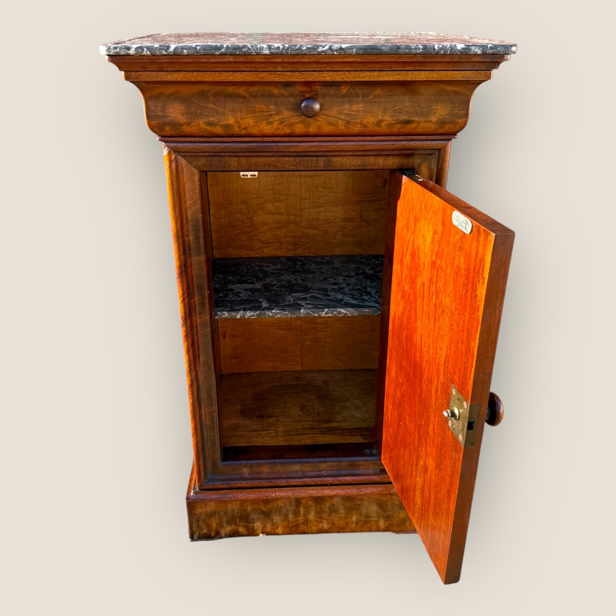 Ecco un comodino francese in mogano in stile Louis Phillips del 1890 circa con un piano in marmo grigio antracite con venature bianche. Sul fregio si trova un cassetto con maniglia a pomello in legno, che si apre per creare uno spazio di
