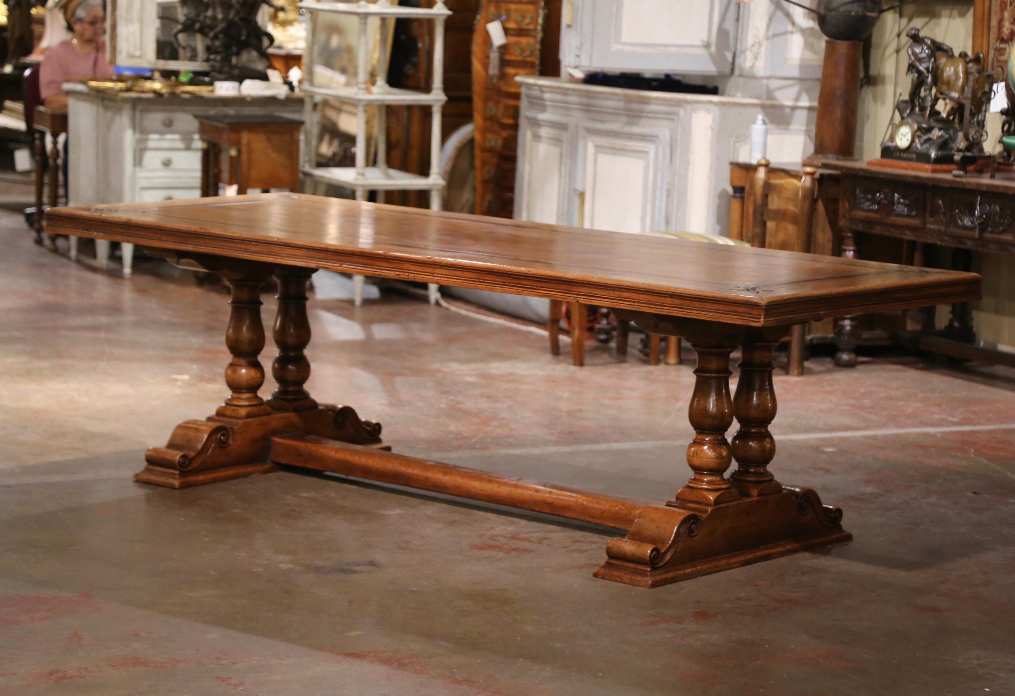 This elegant dining table was crafted in the Pyrenees of France using antique timbers, and following an 18th century design. Over 8 feet long, the large table sits on a trestle base, supported by hand carved turned baluster form support legs ending