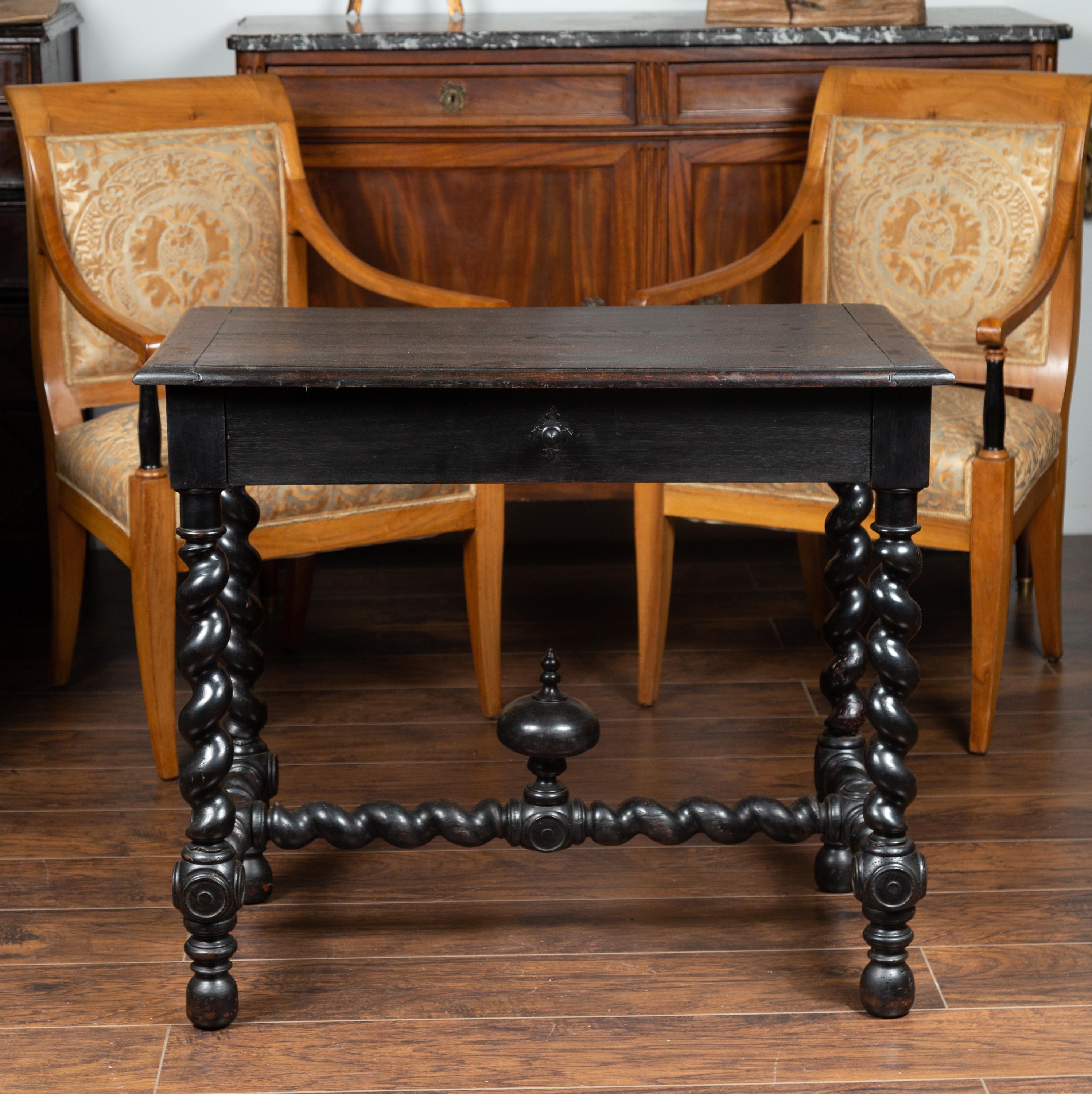 A French Louis XIII style ebonized wood side table from the third quarter of the 19th century, with single drawer, barley twist base and carved finial. Born in France at the end of emperor Napoleon III's reign, this exquisite side table attracts our