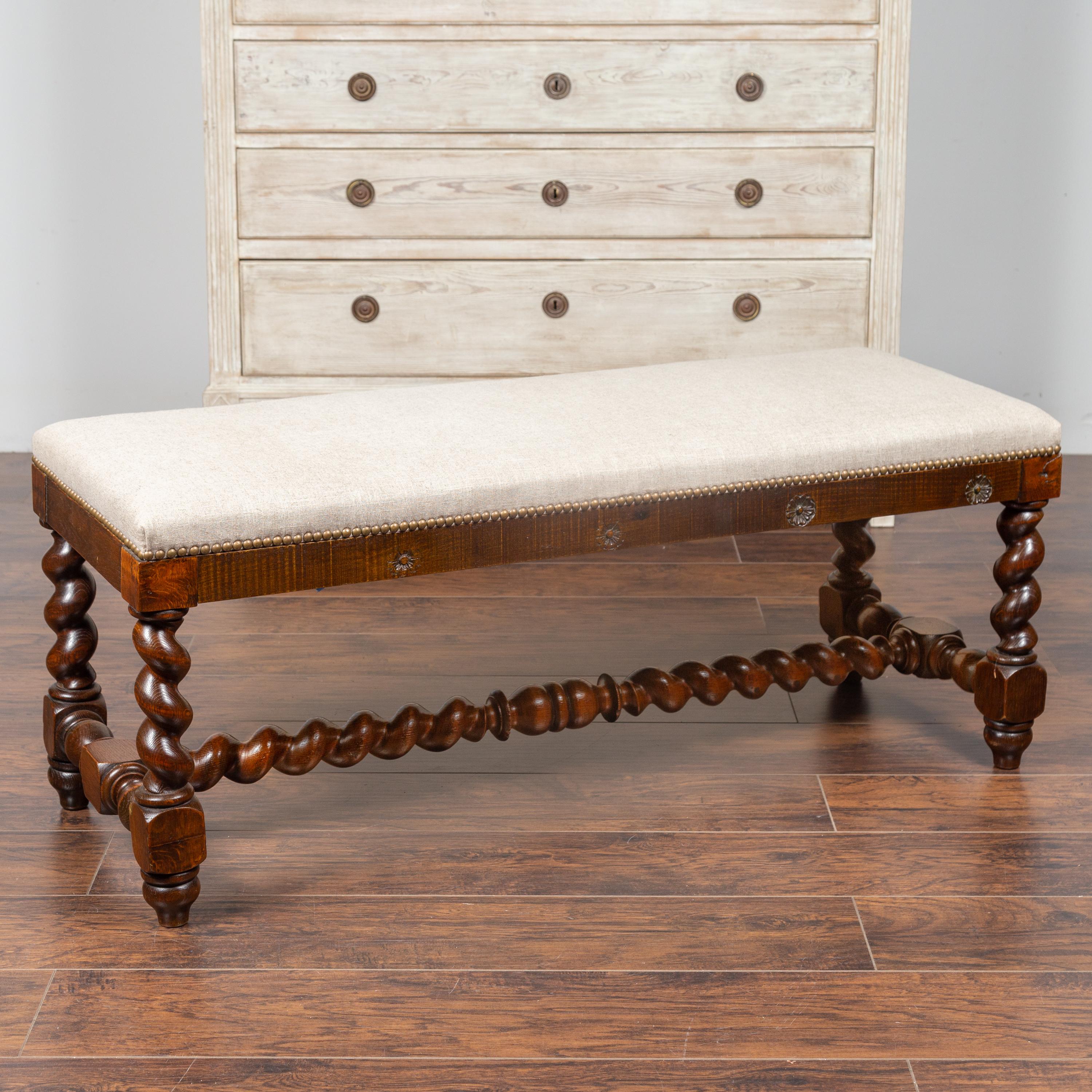 A French Louis XIII style walnut barley twist bench from the late 19th century with new upholstery. Born in the last quarter of the 19th century, this stylish walnut bench features a rectangular seat newly reupholstered with a linen fabric accented