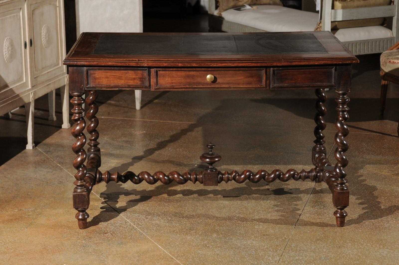 A French Louis XIII style walnut desk from the late 19th century, with leather top, barley twist base and carved finial. Born in France during the last quarter of the 19th century, this French walnut desk features the stylistic characteristics of