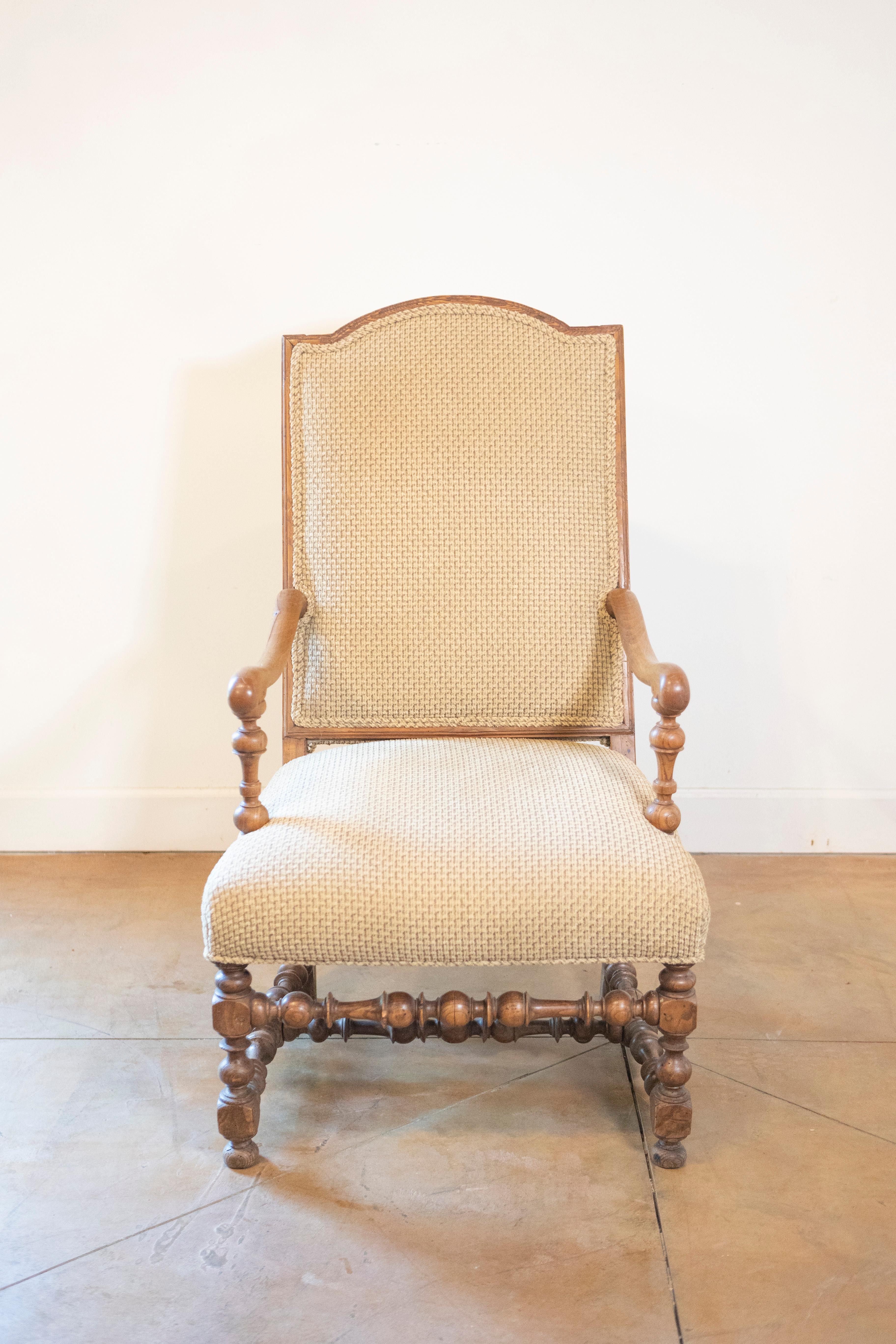 Sillón francés de nogal del siglo XIX, estilo Luis XIII, con respaldo superior arqueado, base torneada y grandes brazos con volutas. Este sillón francés de nogal del siglo XIX, fabricado en el perdurable estilo Luis XIII, es un testimonio de