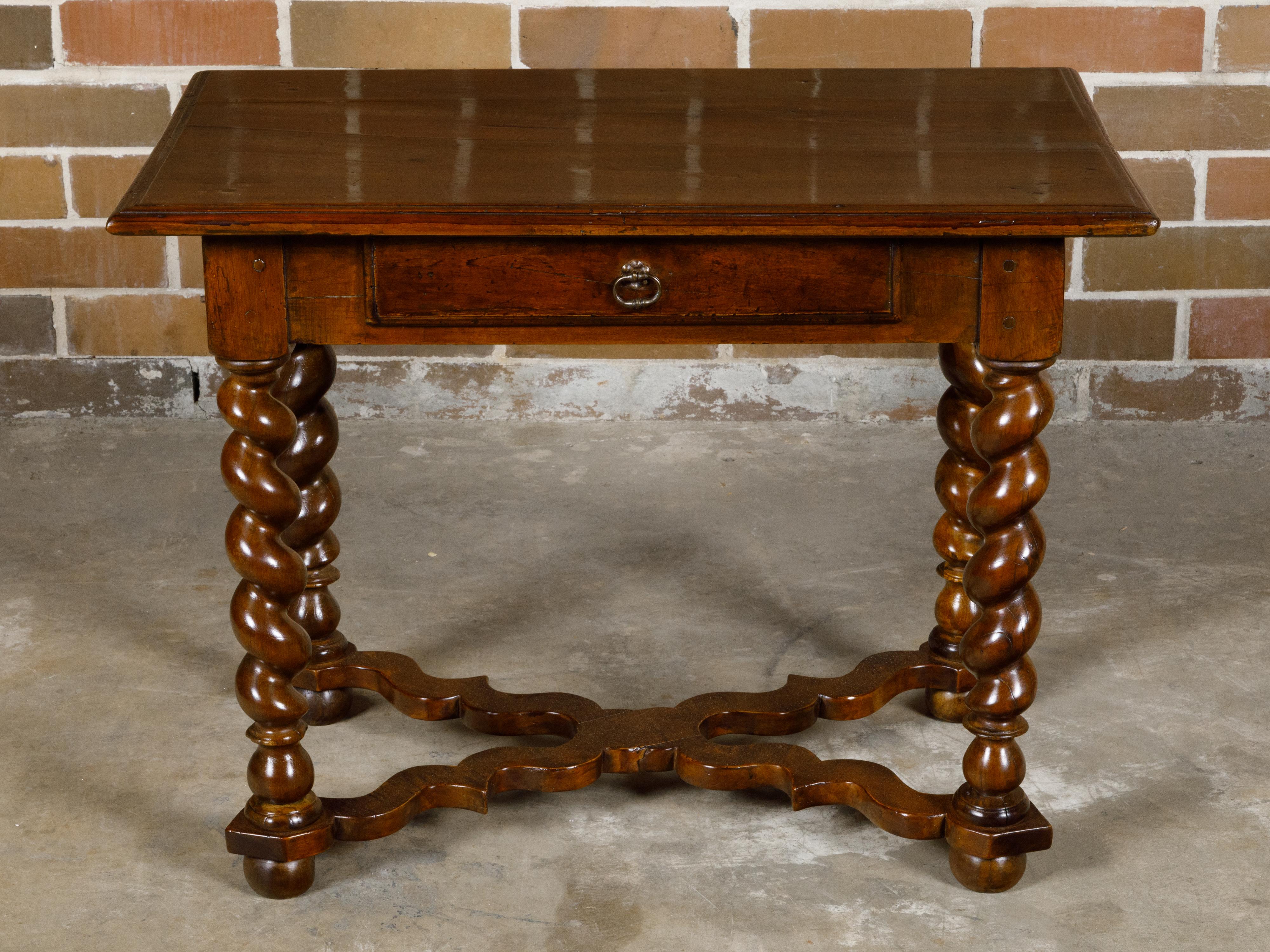 A French Louis XIII style walnut side table from the 19th century with barley twist base, carved X-Form cross stretcher and single drawer. This exquisite French Louis XIII style walnut side table, dating back to the 19th century, marries timeless