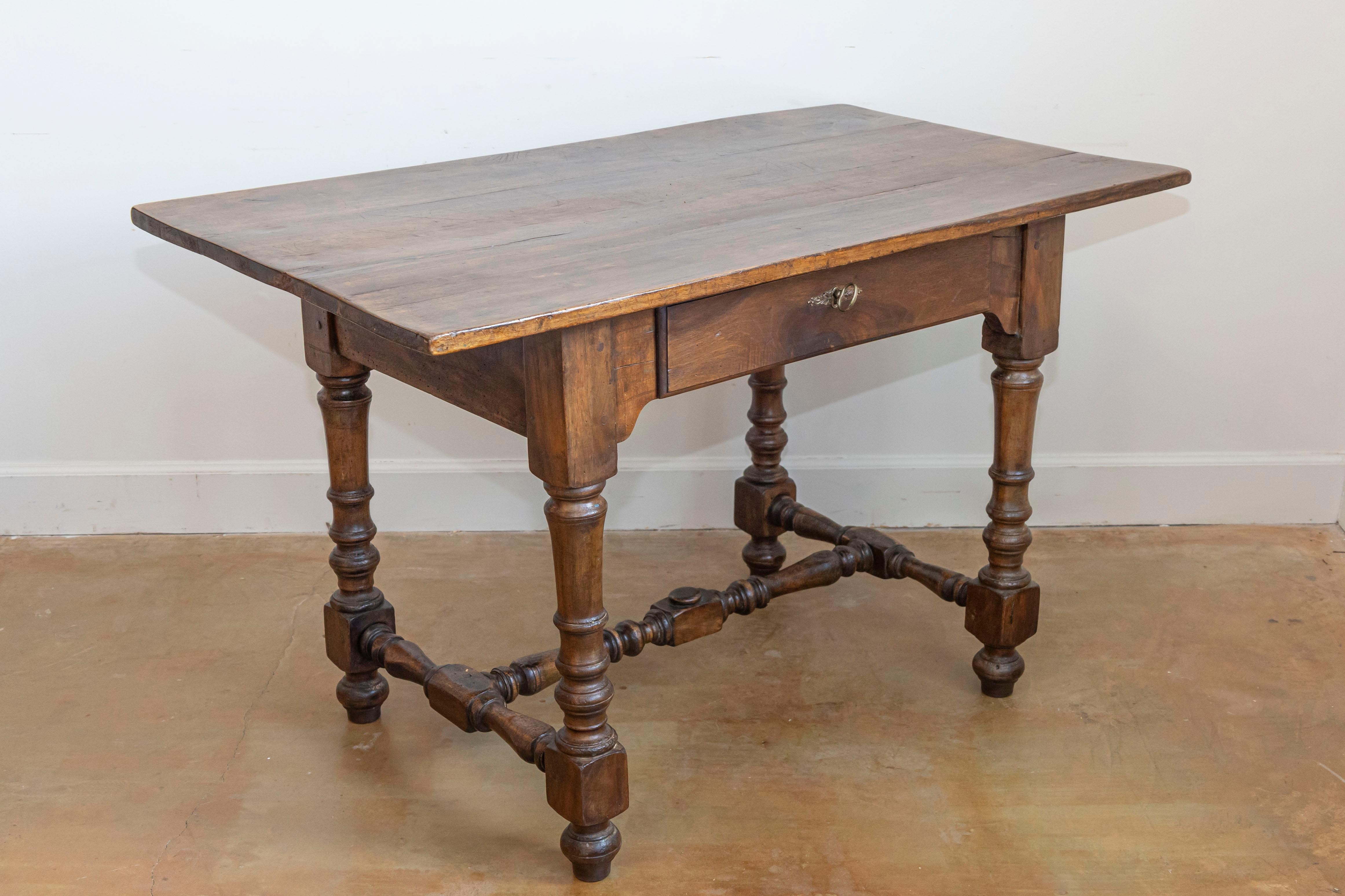 A French Louis XIII style walnut side table from the 19th century, with single drawer, bronze hardware, turned legs and H-Form cross stretcher. Created in France during the 19th century, this walnut table showcases the stylistic characteristics of