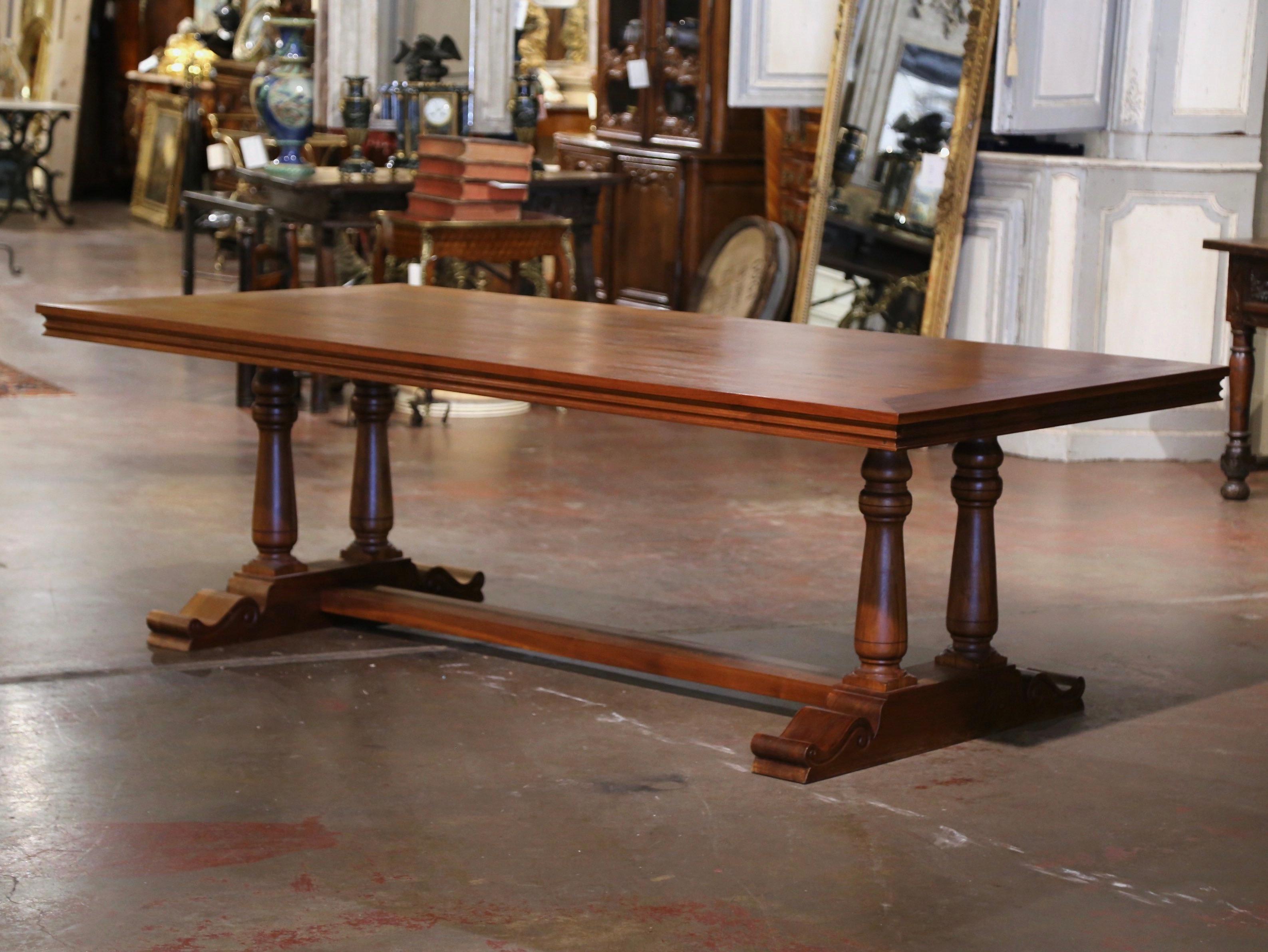 Recibe a tus invitados con estilo en torno a esta gran mesa de comedor de madera de frutal de 2,5 m de largo. Fabricada en Francia, y construida en nogal, la pesada mesa se alza sobre una base de caballete, sostenida por patas de balaustre talladas