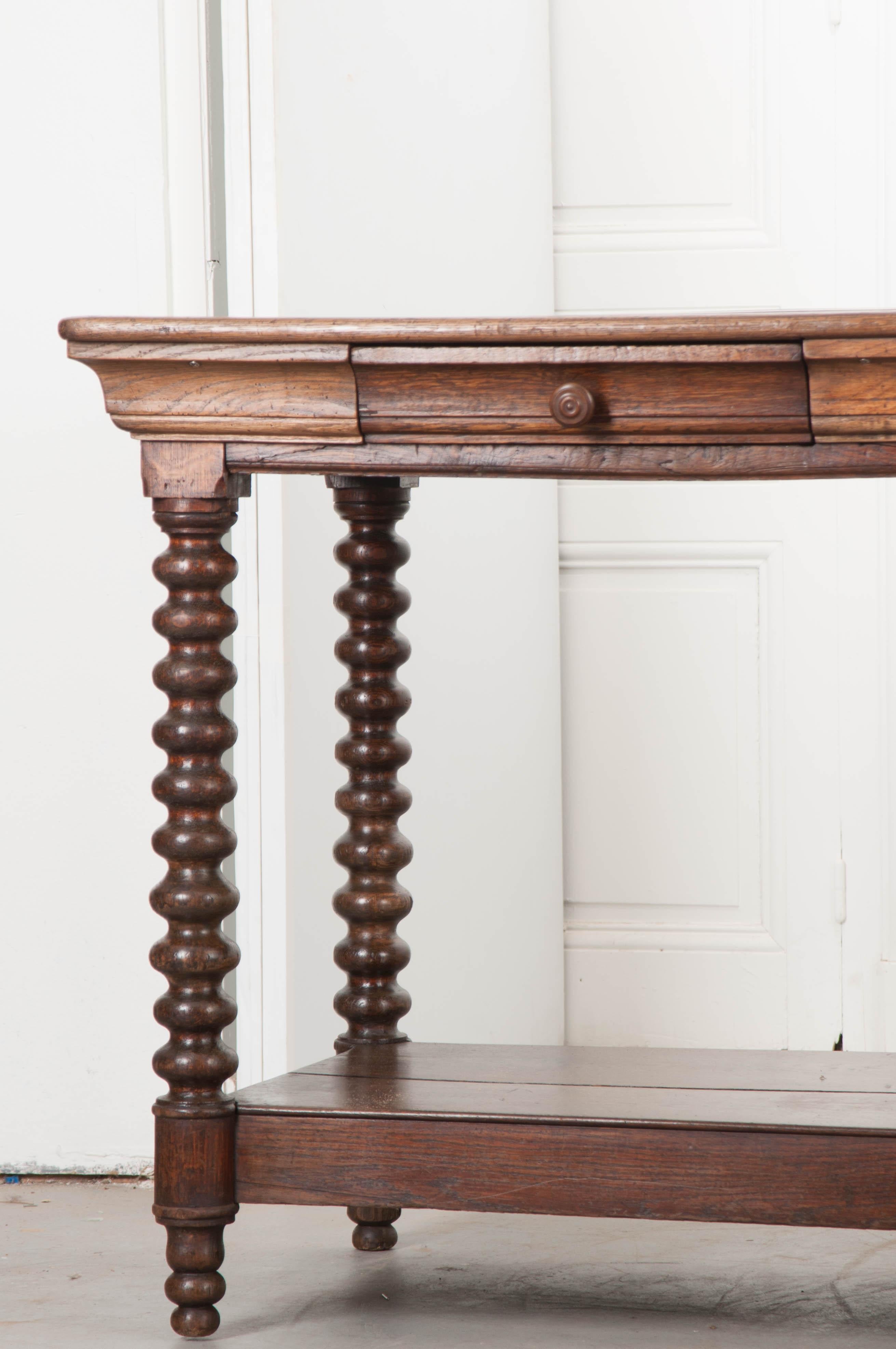 This monumental Louis XIII-style oak drapery table, c.1860’s, is from France and is over twelve feet long! The surface is constructed of three framed planks on either side, having a rounded edge and rests upon a beautifully carved apron with a