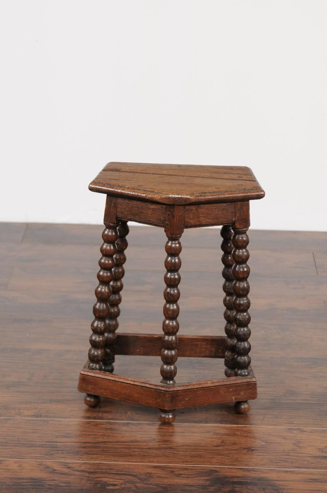 A French Louis XIII style oak bobbin leg stool from the mid-19th century, with polygonal seat and side stretcher. This French oak stool features a planked polygonal-shaped seat, raised on five exquisite bobbin legs, typical of the Louis XIII style.