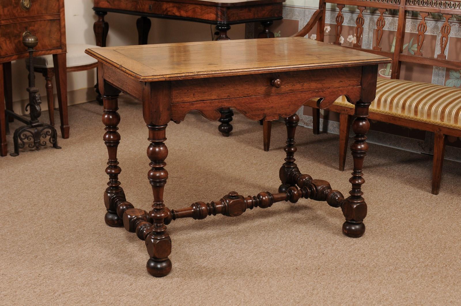 The French Louis XIII style walnut table featuring drawer, carved shaped apron and turned legs or stretcher terminating in bun feet.

 