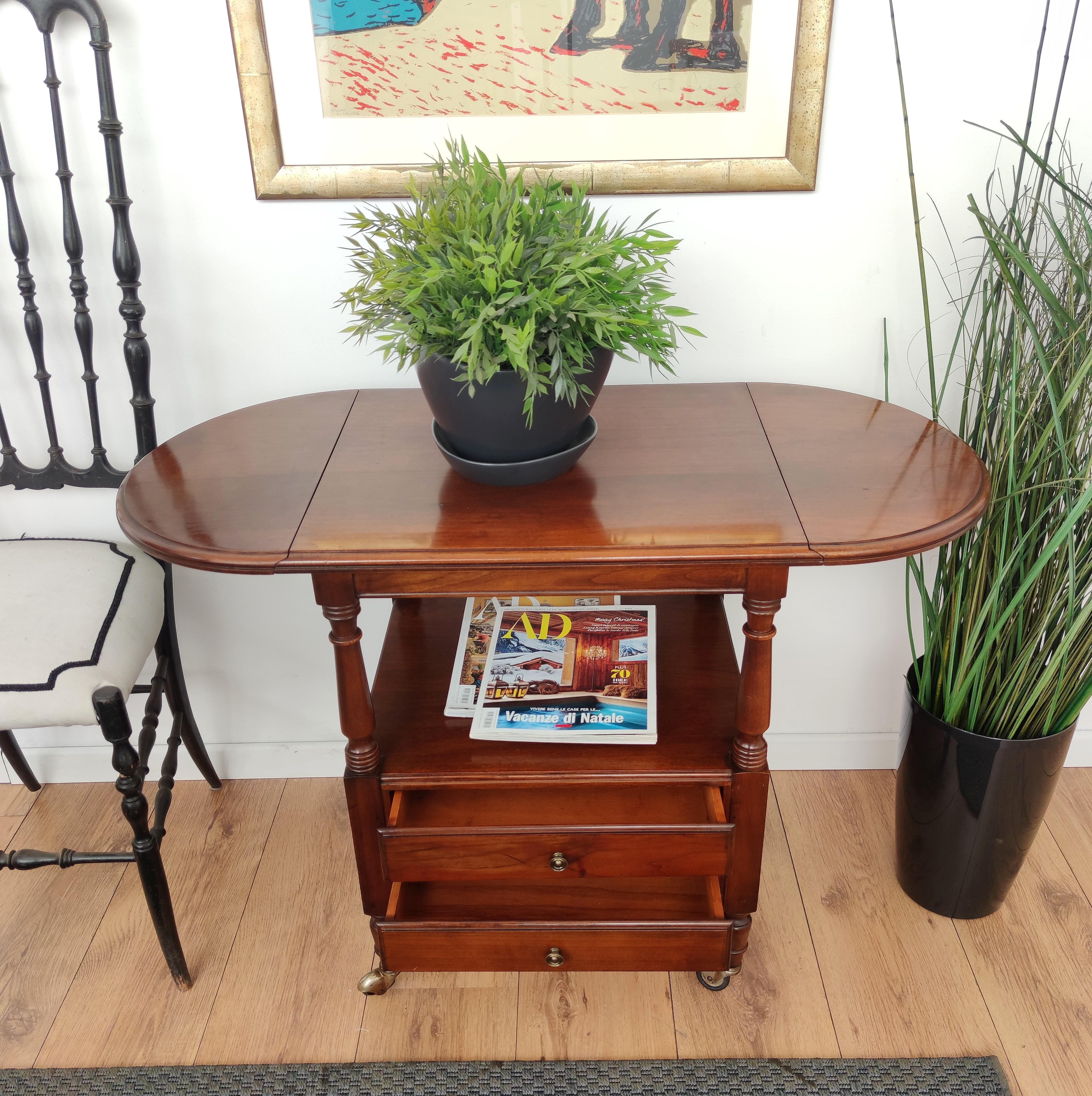 Beautiful French Louis XIII style walnut wood side table features demilune folding sides and great classic details in the trim molded top frame as well as the tapered legs and brass wheels final. This end or side table has a lower shelf and 2