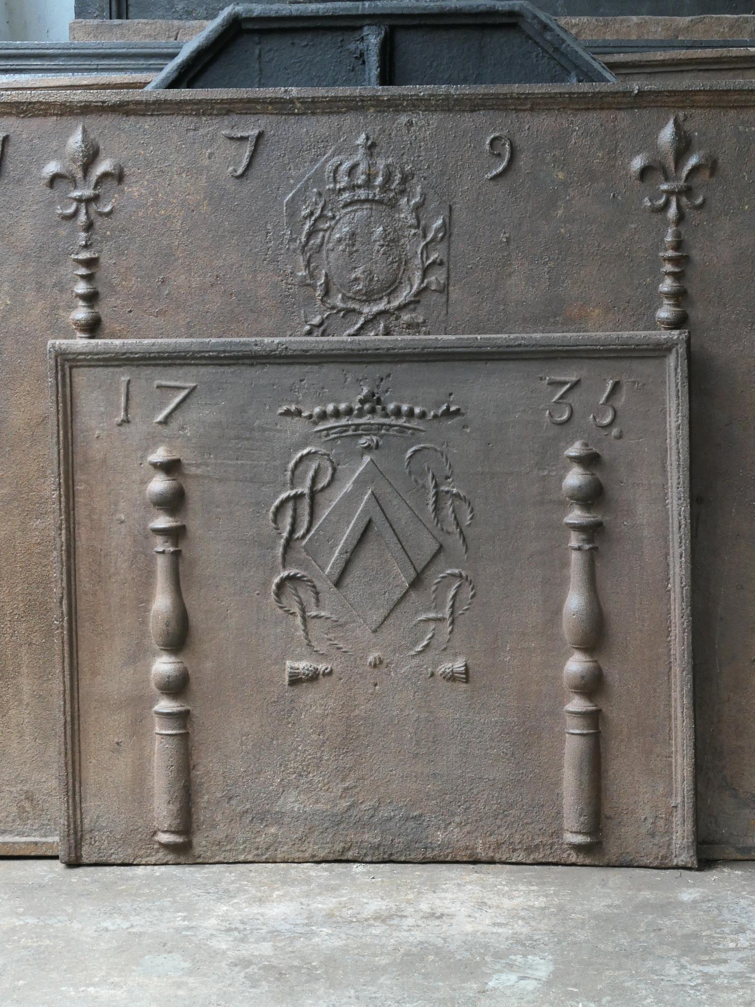 French Louis XIV period fireback with a coat of arms. The coat of arms is flanked by two pillars, which refer to the club of Hercules. They stand for strength and the unknown. The date of production, 1735, is also cast in the fireback. 

The