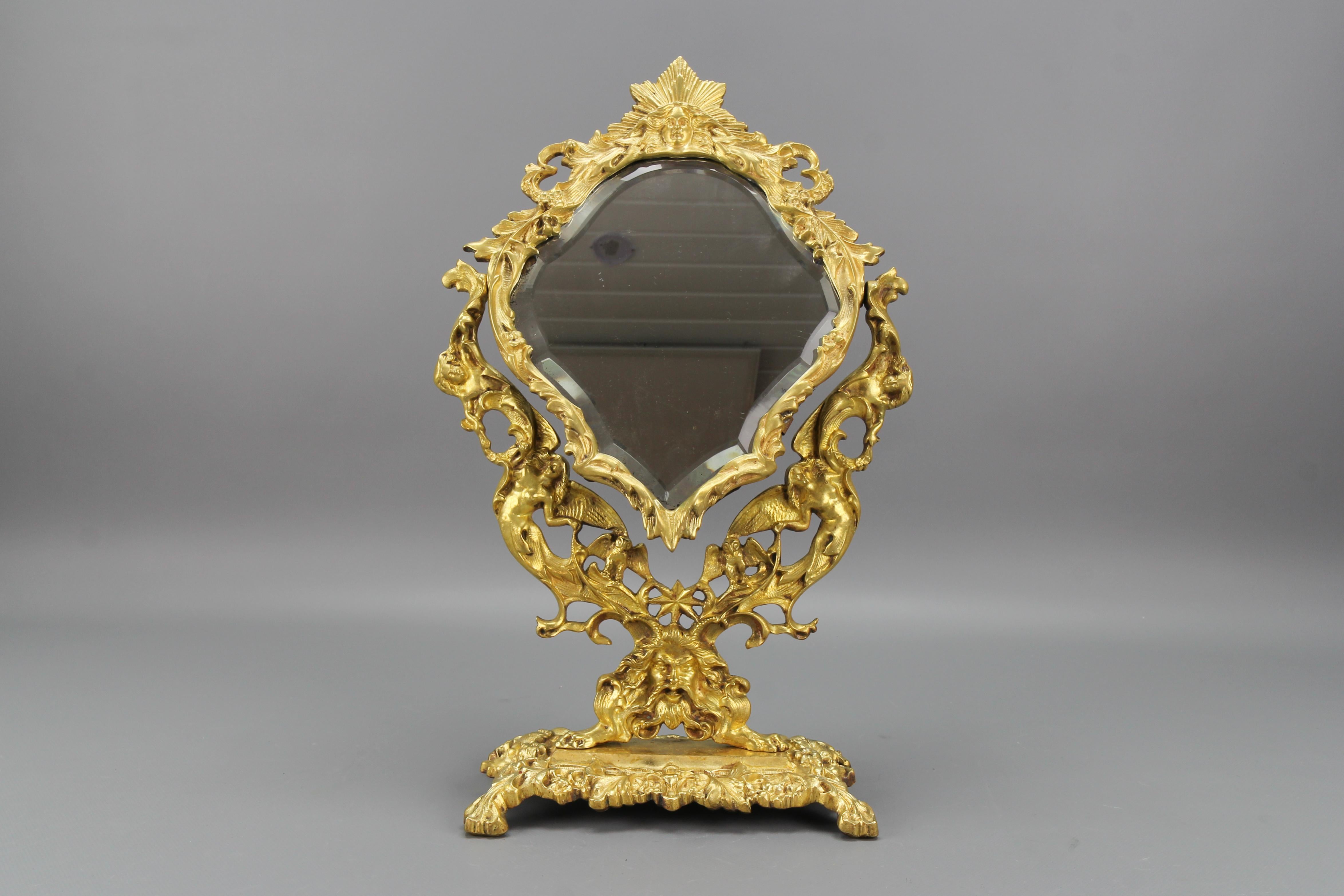 French Louis XIV Style bronze and brass faceted desktop mirror from the 1920s
Adorned with typical Louis XIV-style symbols, allegorical figures, floral, and foliate motifs around the beautifully shaped and faceted mirror, this splendid ornate
