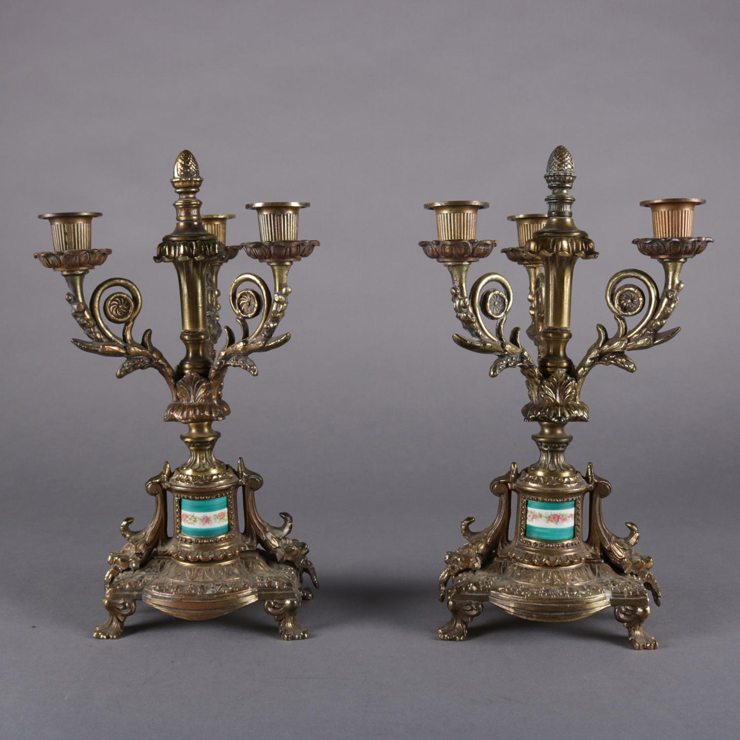 Pair of antique French Louis XIV style candelabra features bronzed base with Sevres school painted porcelain cylindrical insert below three scroll and foliate form arms terminating in candle sockets and surrounding central pineapple finial, circa