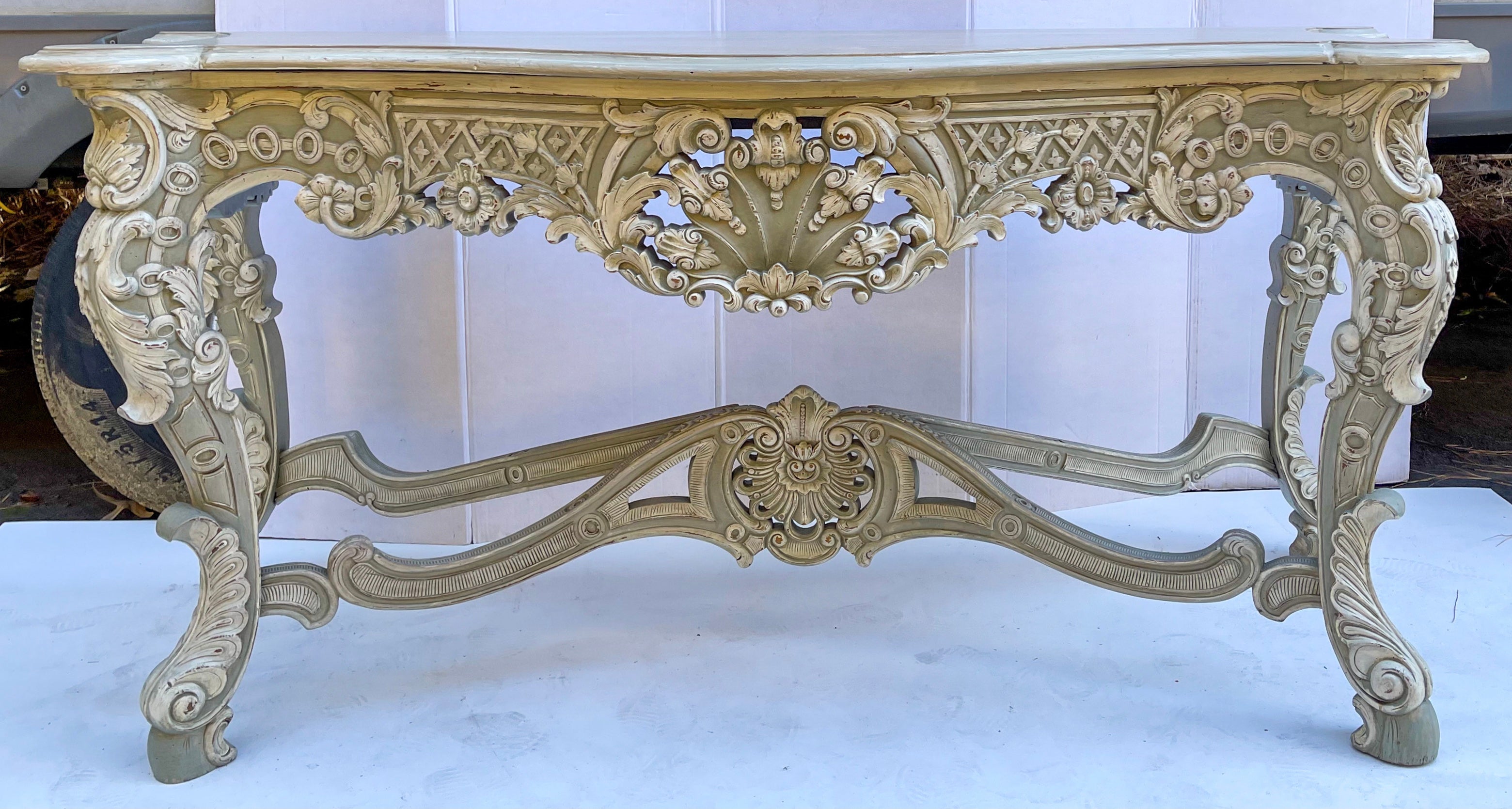 This is a show stopper! This is a 20th century French style heavily carved mahogany console table with an amazing custom painted finish in a distressed French gray and ivory. It is unmarked and in very good condition.