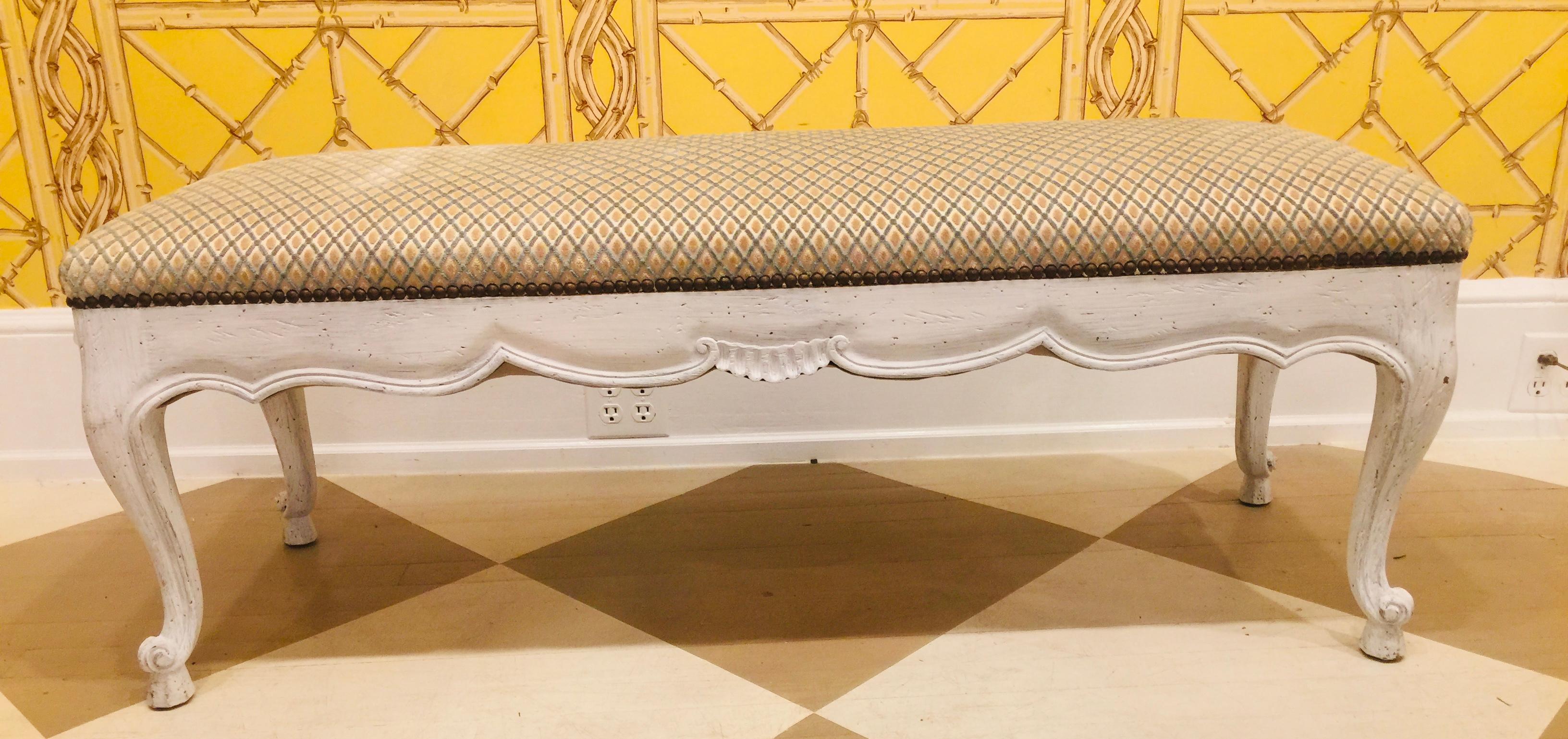 French Louis XIV style chalked white finish hand carved wooden bench
having a beige diamond pattern velvet upholstered top and trimmed with brass nail
heads.
     