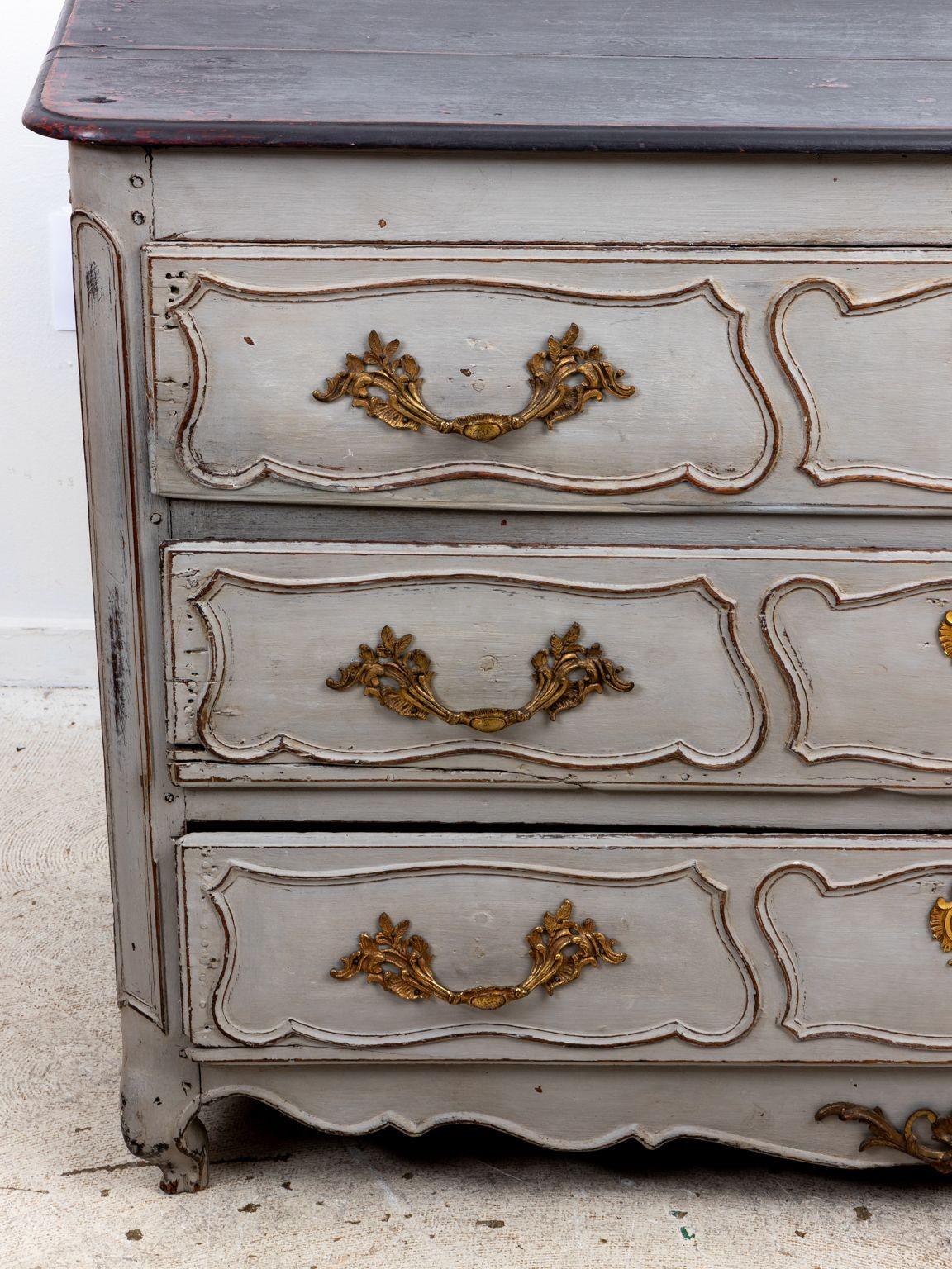 A late 19th Century Louis XIV style French commode with later gray paint. Brass pulls and escutcheons on three drawers. Darker gray painted top. Please note of wear consistent with age.
