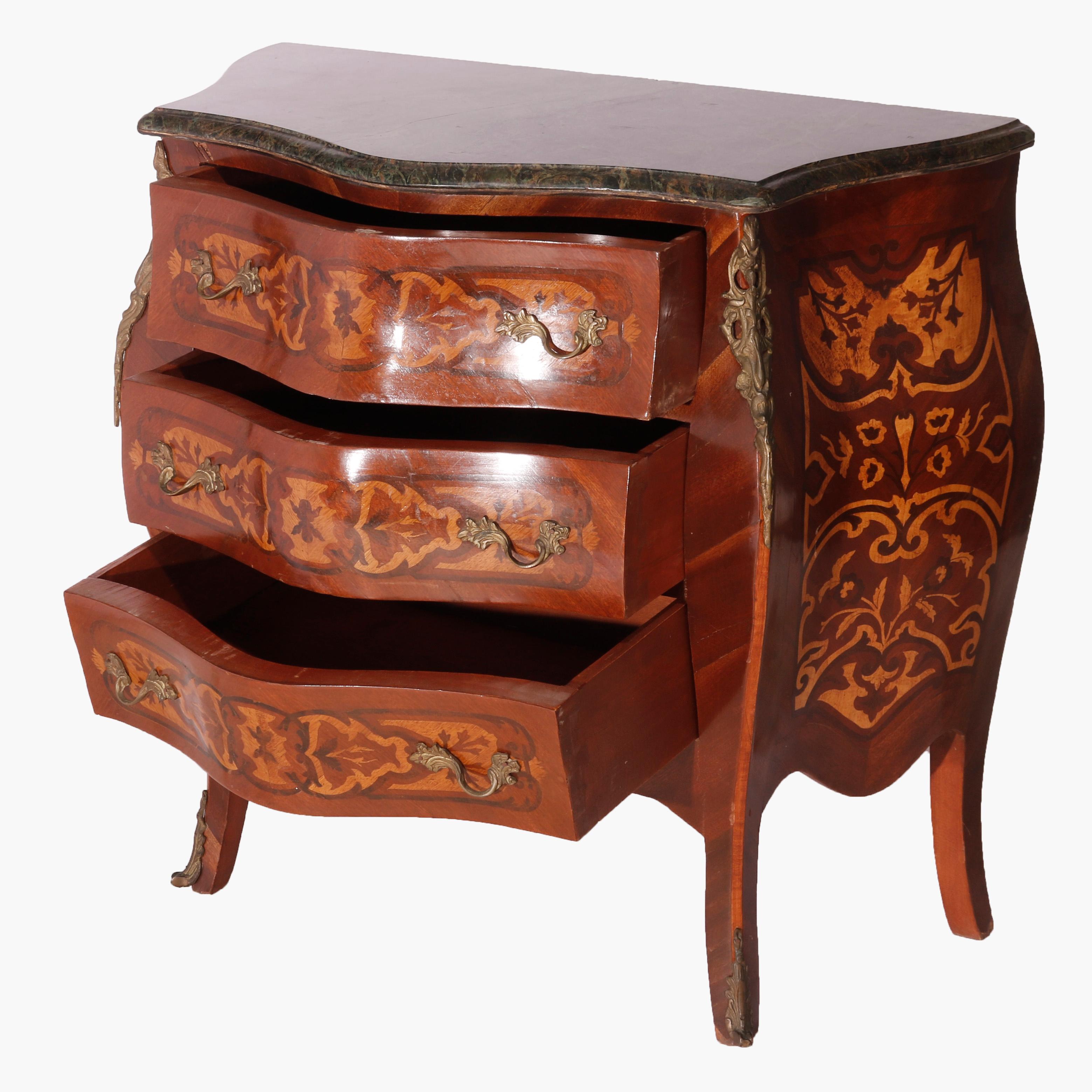 A French Louis XIV style commode offers kingwood construction in bombe form with marble top over case having two drawers with satinwood marquetry in floral and foliate design throughout, highlighted with foliate cast ormolu mounts , 20th