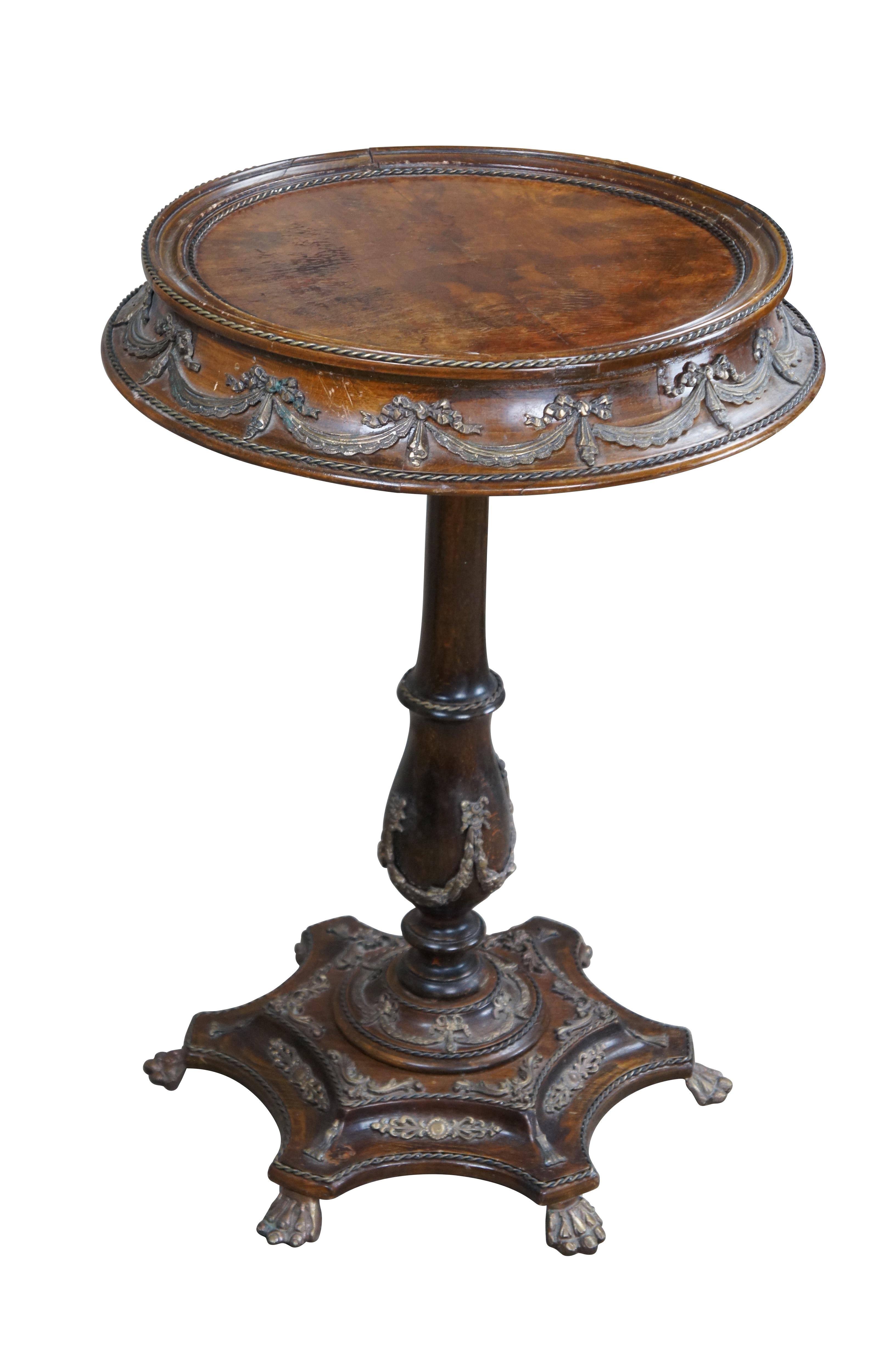 An impressive French Louis XIV style table, circa 1970s. Features a round form with inset matchbook veneered mahogany top, braised brass and bronze ormolu swags. The table is supported by a turned baluster leading to a hexagram base ornate ormolu