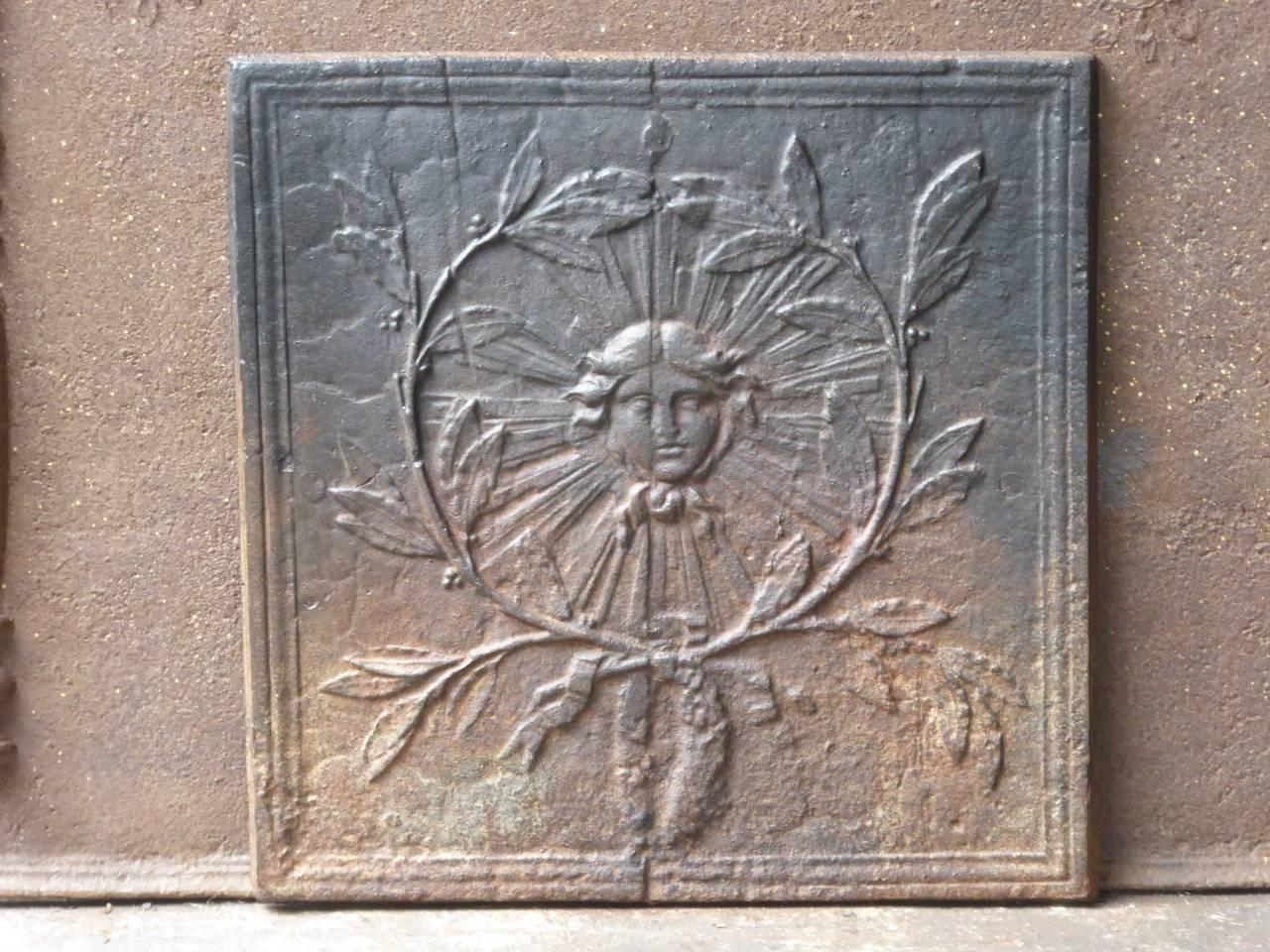 French Louis XIV style fireback with a sun surrounded by olive branches. The sun symbolizes king Louis XIV and the olive branches symbolize peace.
