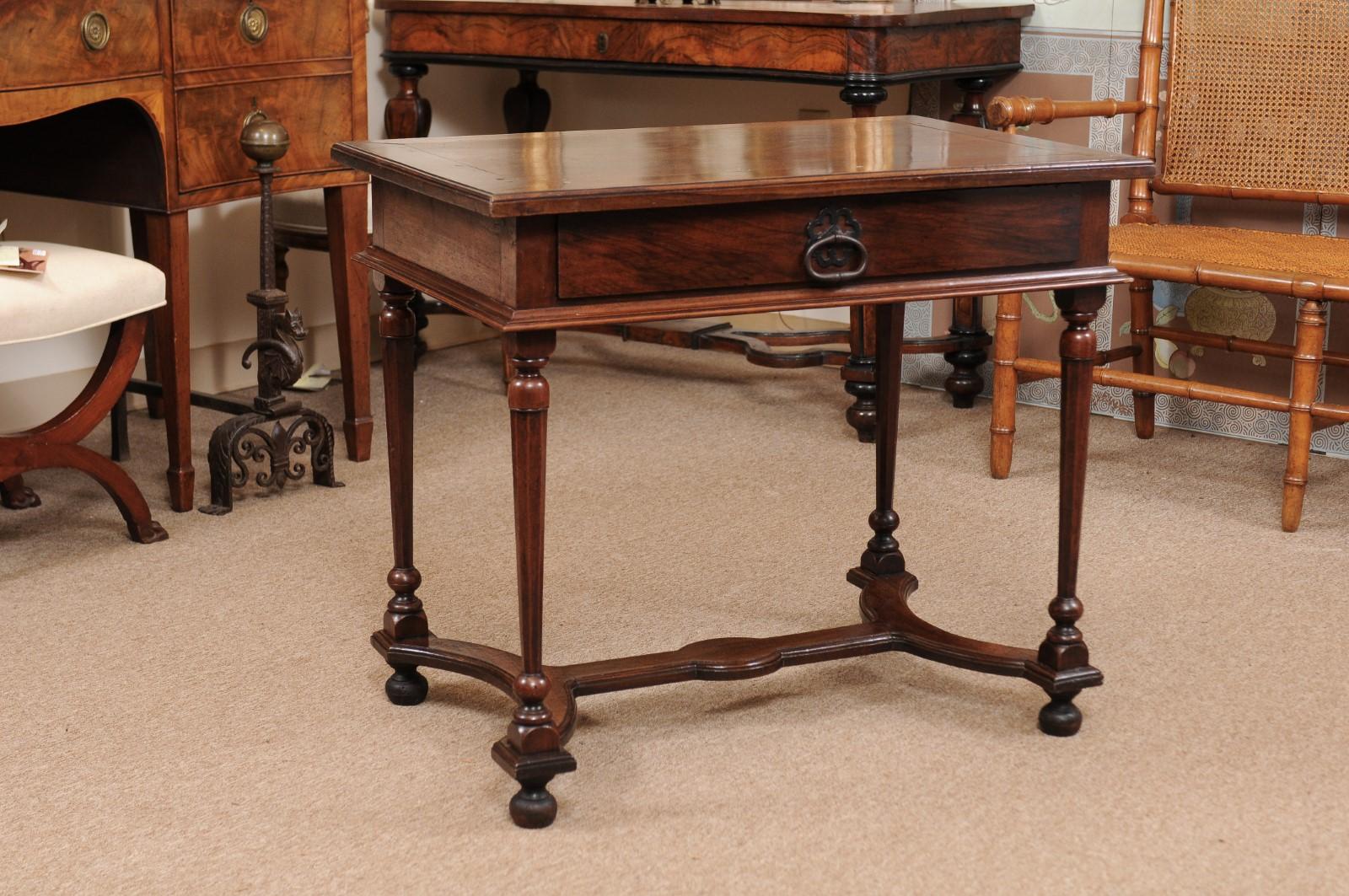 A Louis XIV walnut side table finished on all sides with molded edge rectangular top above larger center drawer in frieze. The turned tapered legs below with shaped stretcher ending in bun feet.