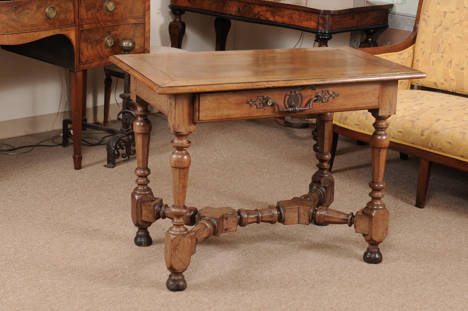 An early 18th century Louis XIV walnut table with rectangular molded top, long drawer in frieze with intricate wrought iron center pull, and turned legs below joined by X-form stretcher ending in bun feet. The table is finished on all sides. 

 