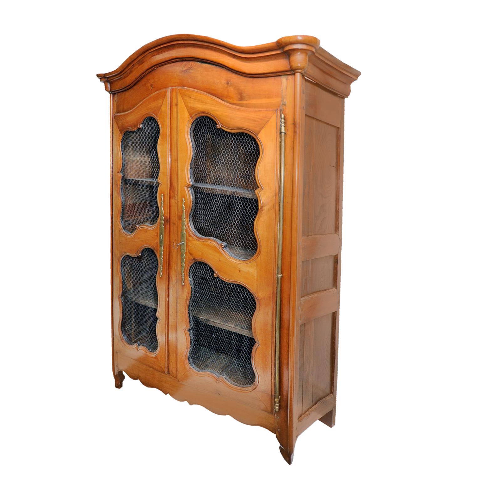 This is a superb 18th century, Louis XV French pale cherrywood cupboard or bookcase of wonderful color with wire grills and featuring superb original brass furniture, hinges, escutcheons, lock and key, circa 1760.
 