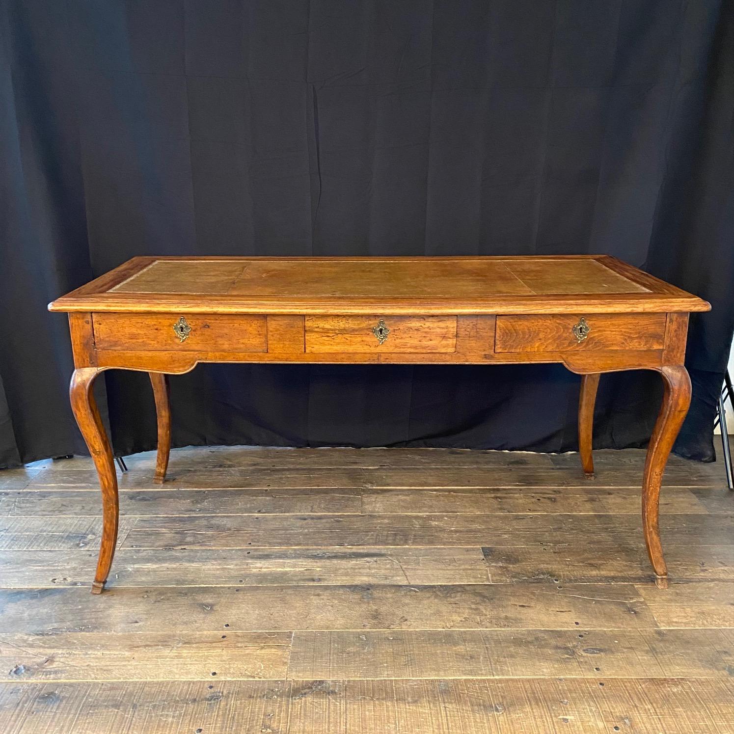 Elegant French Louis XV 19th century walnut three-drawer (dovetailed) desk from Avignon with embossed leather top, original key and cabriole legs. This remarkable desk, crafted from walnut and featuring a rich original embossed leather top and