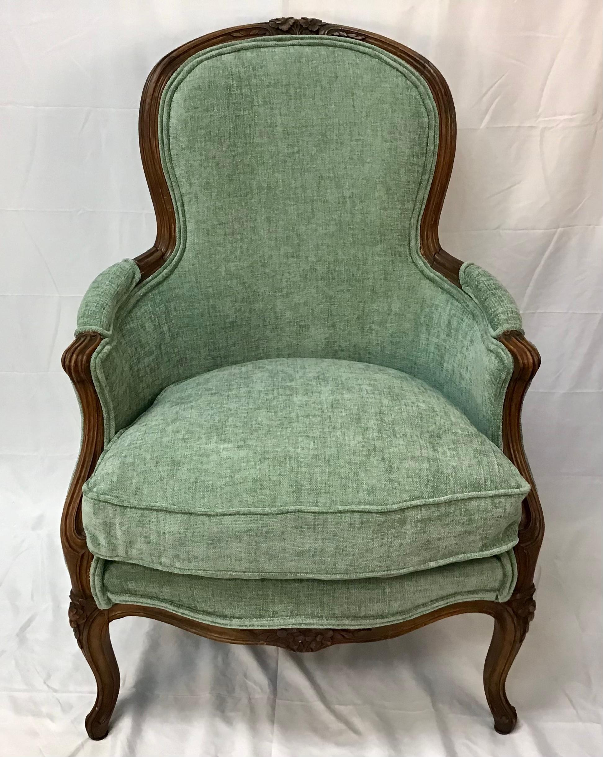 This French bergere has the typical carved details of Louis XV period. This chair is finely hand carved in walnut with flowers and intricate mouldings. The bergere has an arched, padded back and loose cushioned seat and rests on elegant cabriolet