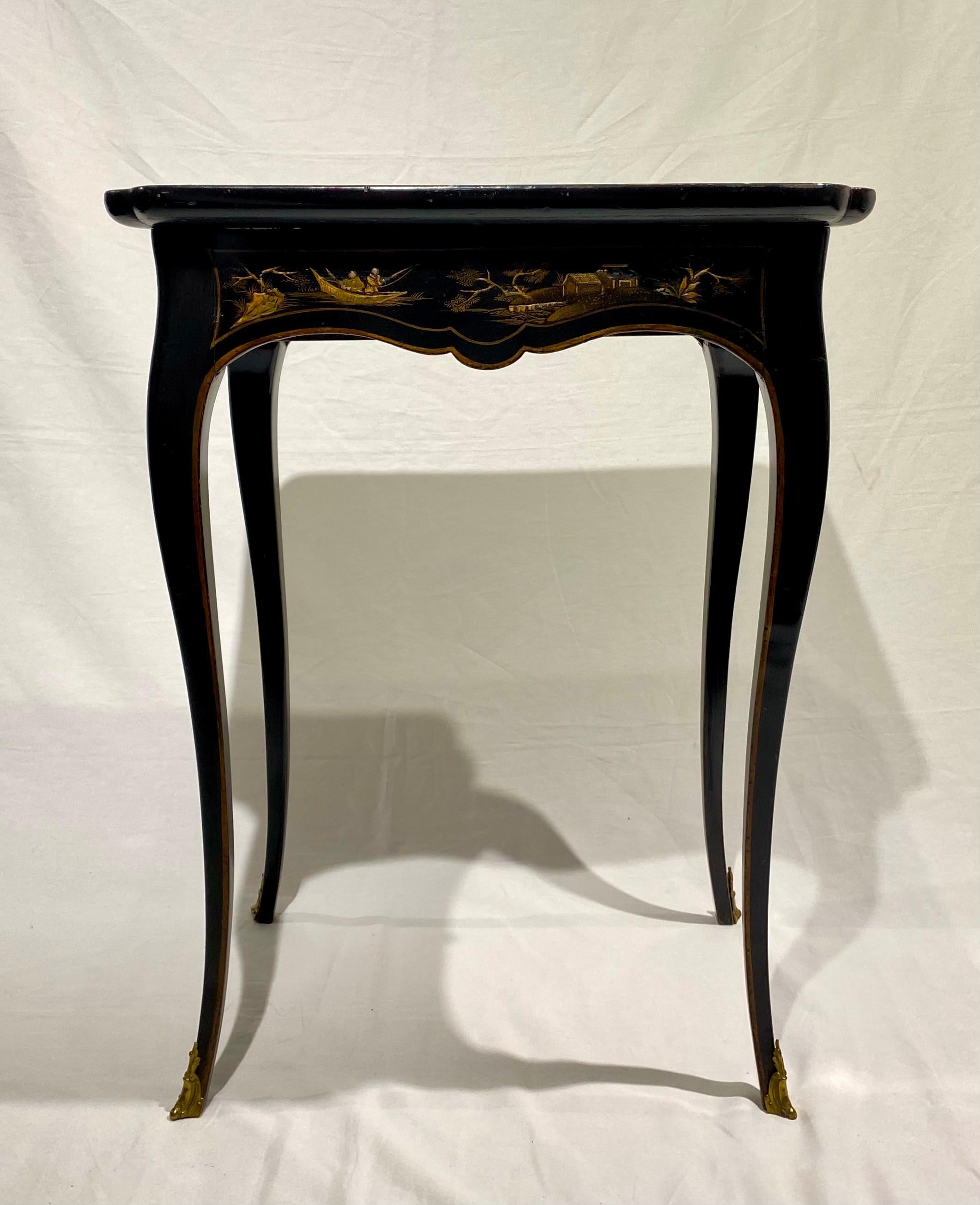 A Louis XV black and gilt Japanned occasional table, mid-18th century, with later restorations to the top. The dished tray (cabaret) adorned with raised, classic representations of fishing boats, fishermen, checker players and pagodas depicted in a