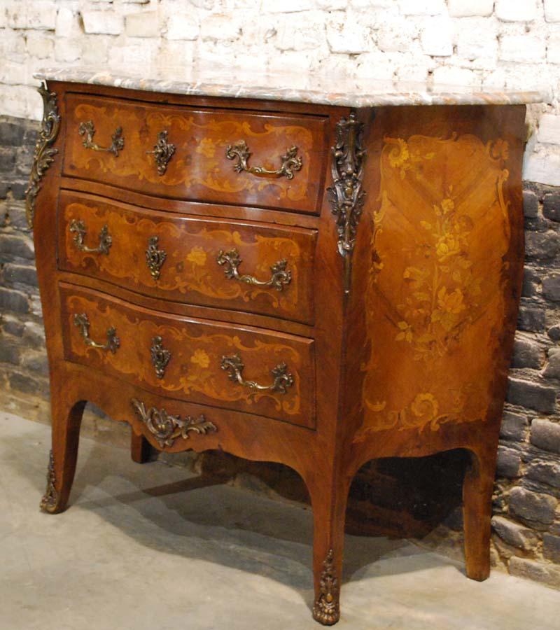 A French dresser from the early 20th century veneered with mahogany
The dresser or commode has a beautifully curved (bombe) front with three drawers. The mahogany veneer is made in cross band and is inlaid with natural and floral motifs typical for