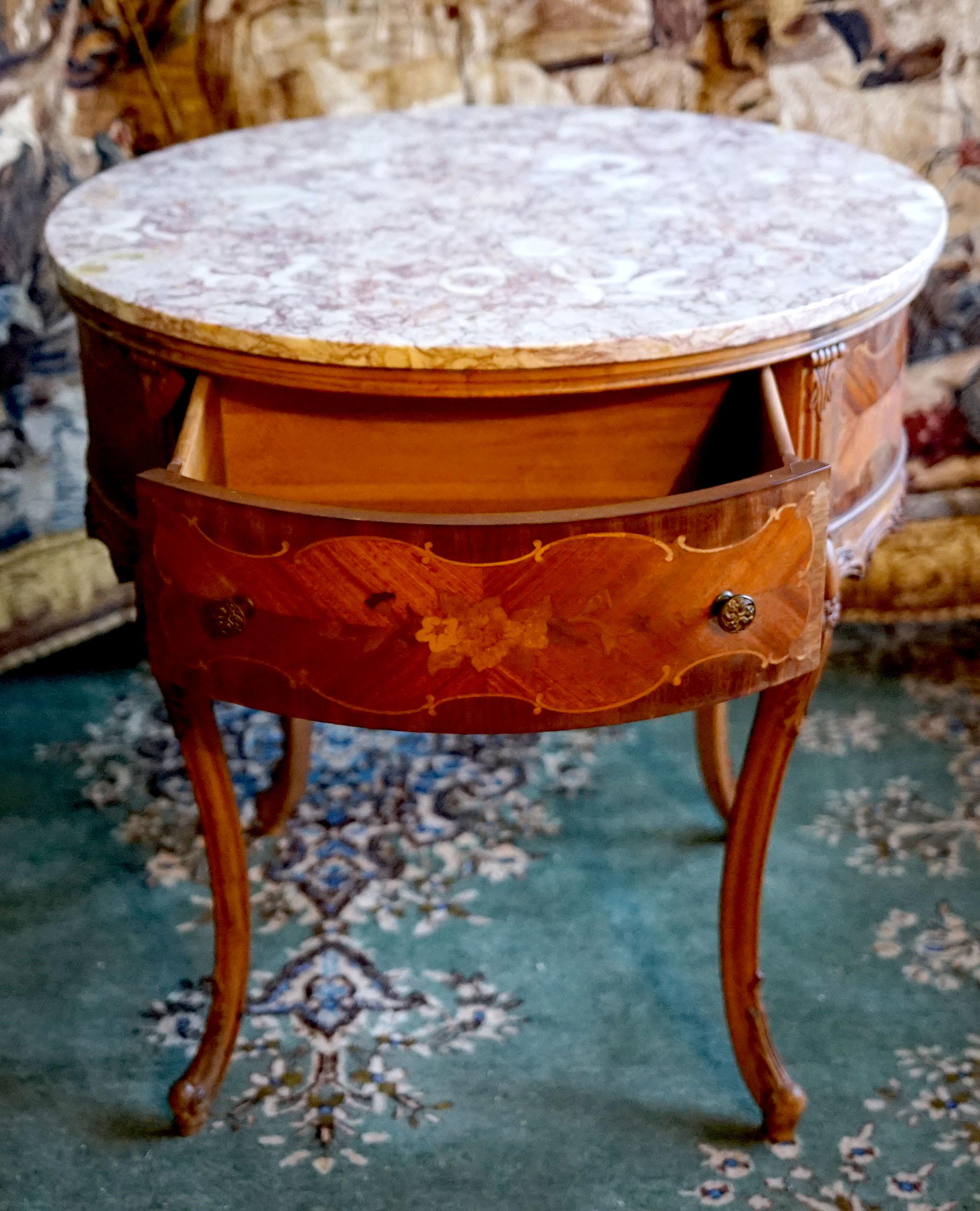 Antique Louis XV style round center table produced between 1875 and 1900 is stunning. It is parcel gilt parquetry, marquetry and inlaid satinwood, which is surmounted by a circular Brêche Violette marble top. The table includes two deep drawers, but